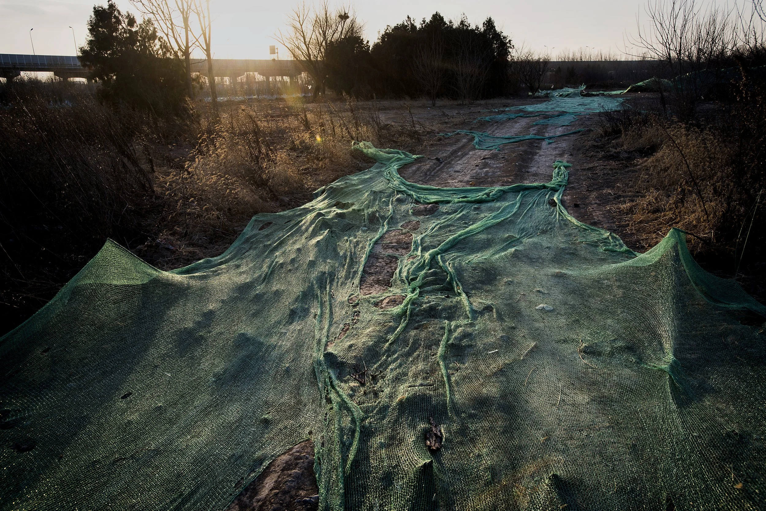   Outskirts .  Beijing, China, 2017.  Dust covers for a dirt road 