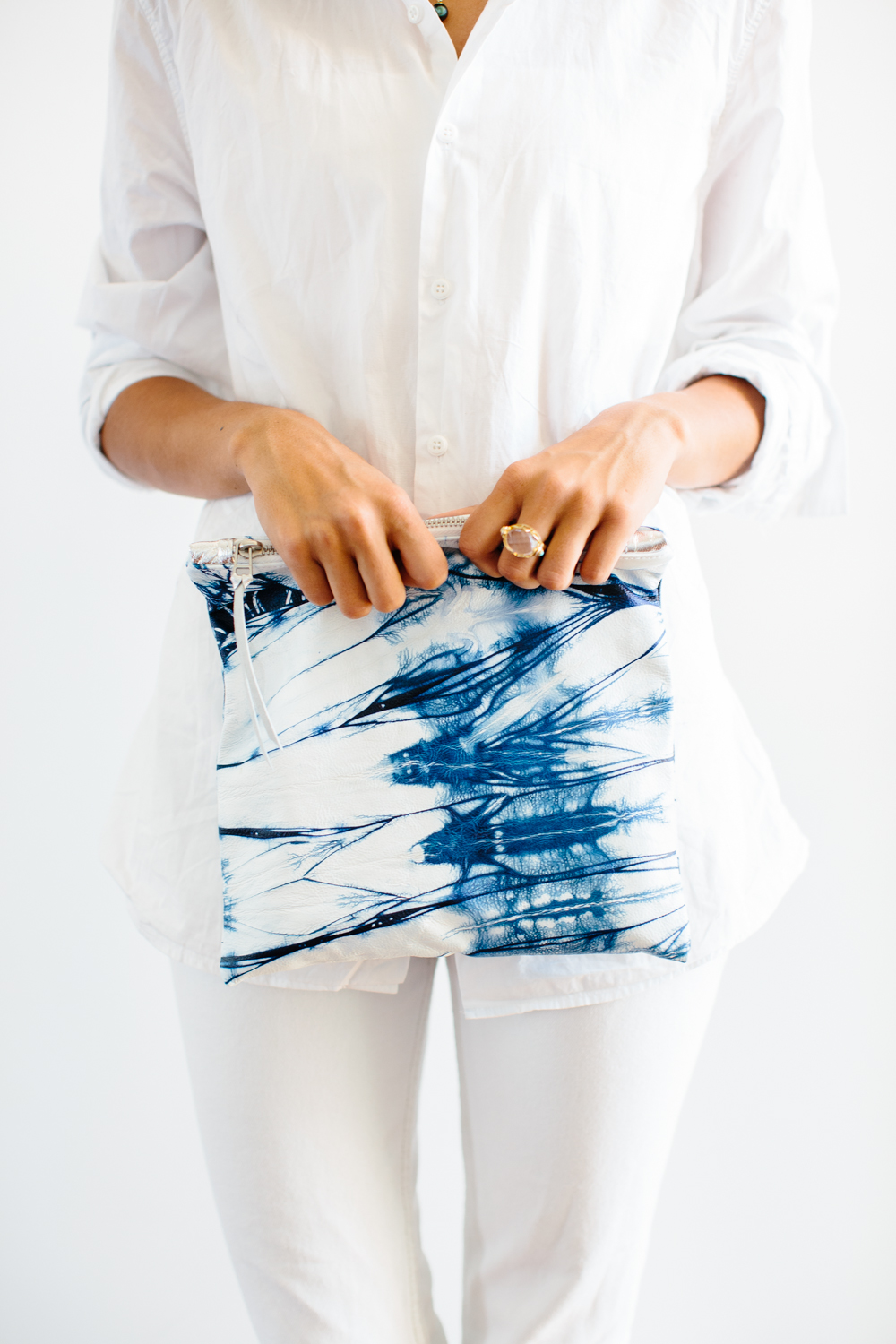 A model in white shirt and jeans holding a blue-white KARMME clutch dyed in the Japanese Shibori technique