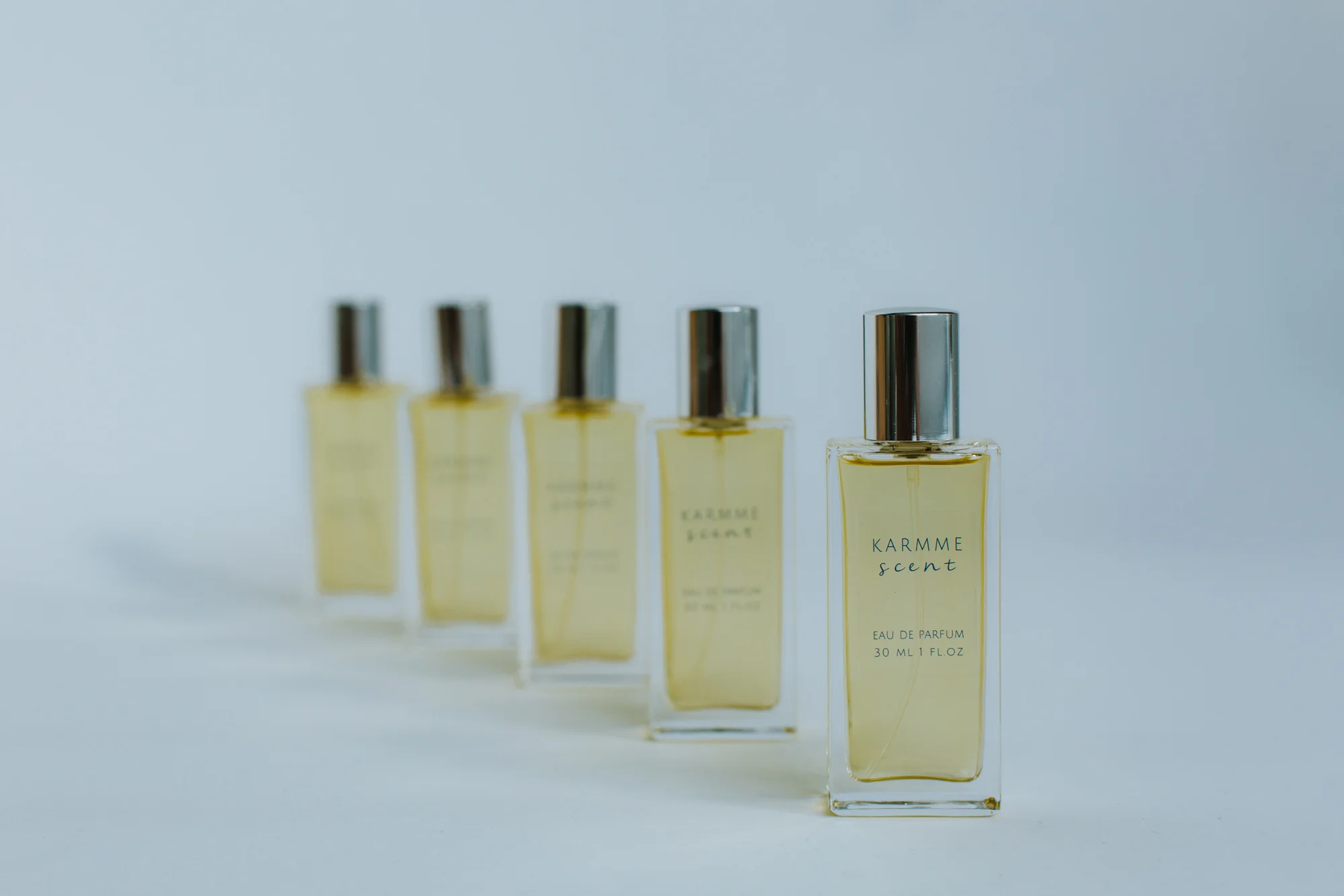 Five bottles of the fragrance KARMME Scent in front of a white background