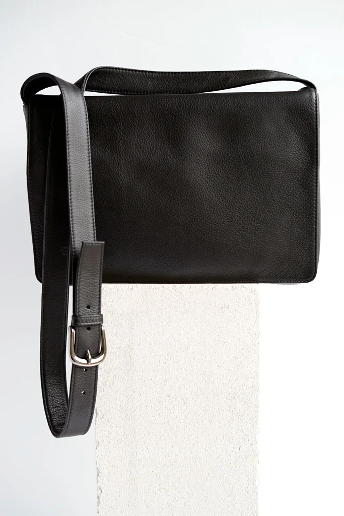 A black leather crossbody bag in front of a white background
