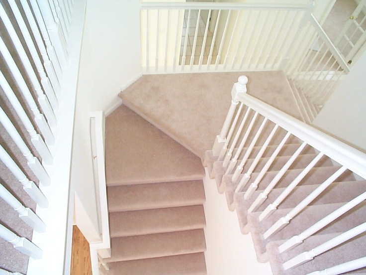 A sense of light and space created by the white painted balusters and bannisters and light coloured carpet.