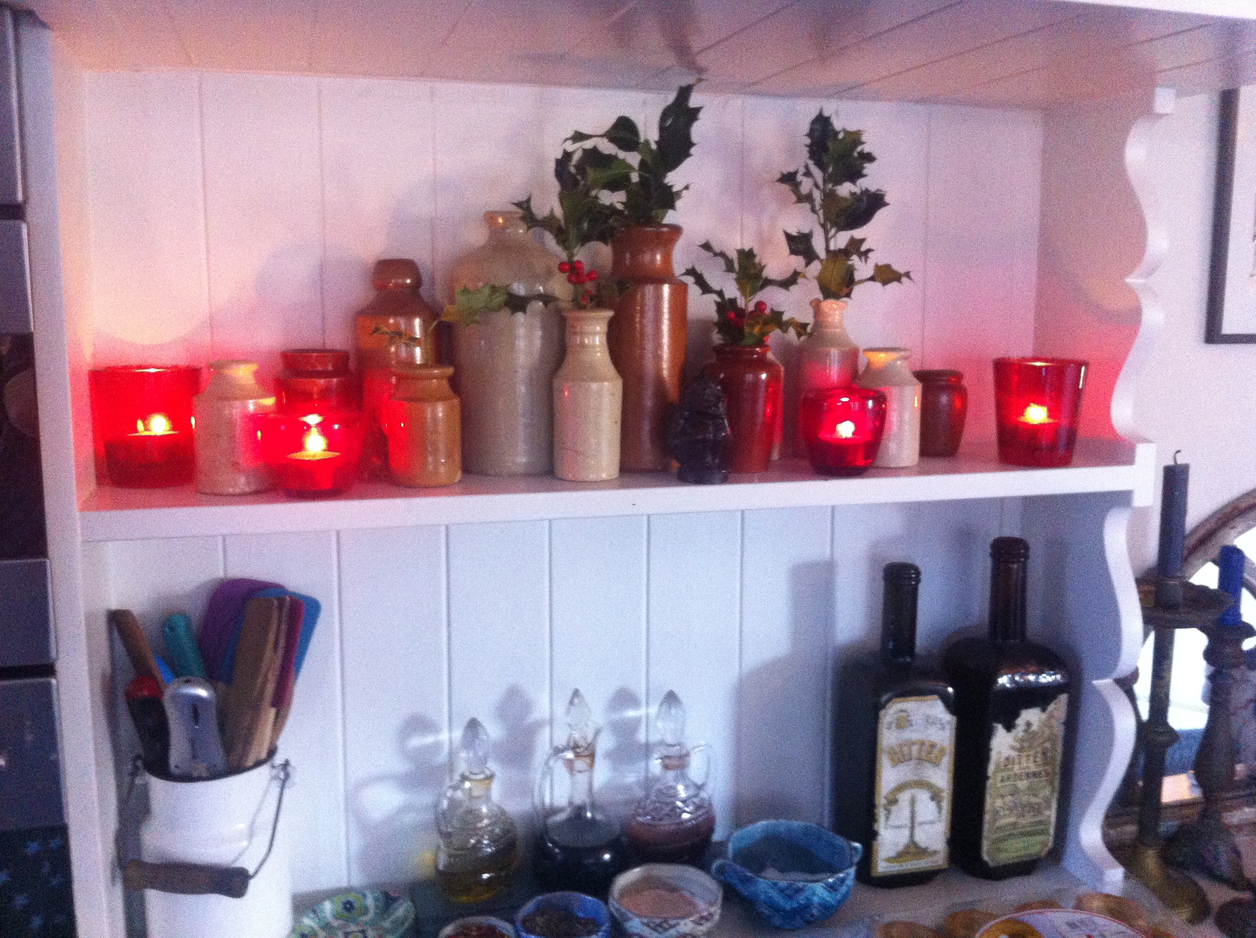  Tiny sprigs of holly in vintage bottles lit by a few candles 