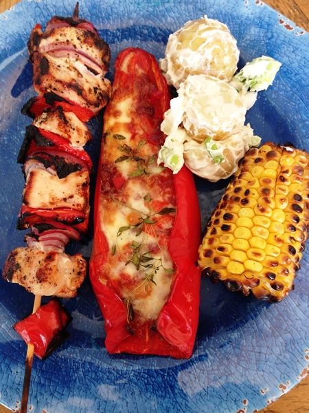  A main course of chicken breast skewers and sweet corn on the barbecue, stuffed peppers with taleggio and a potato salad 