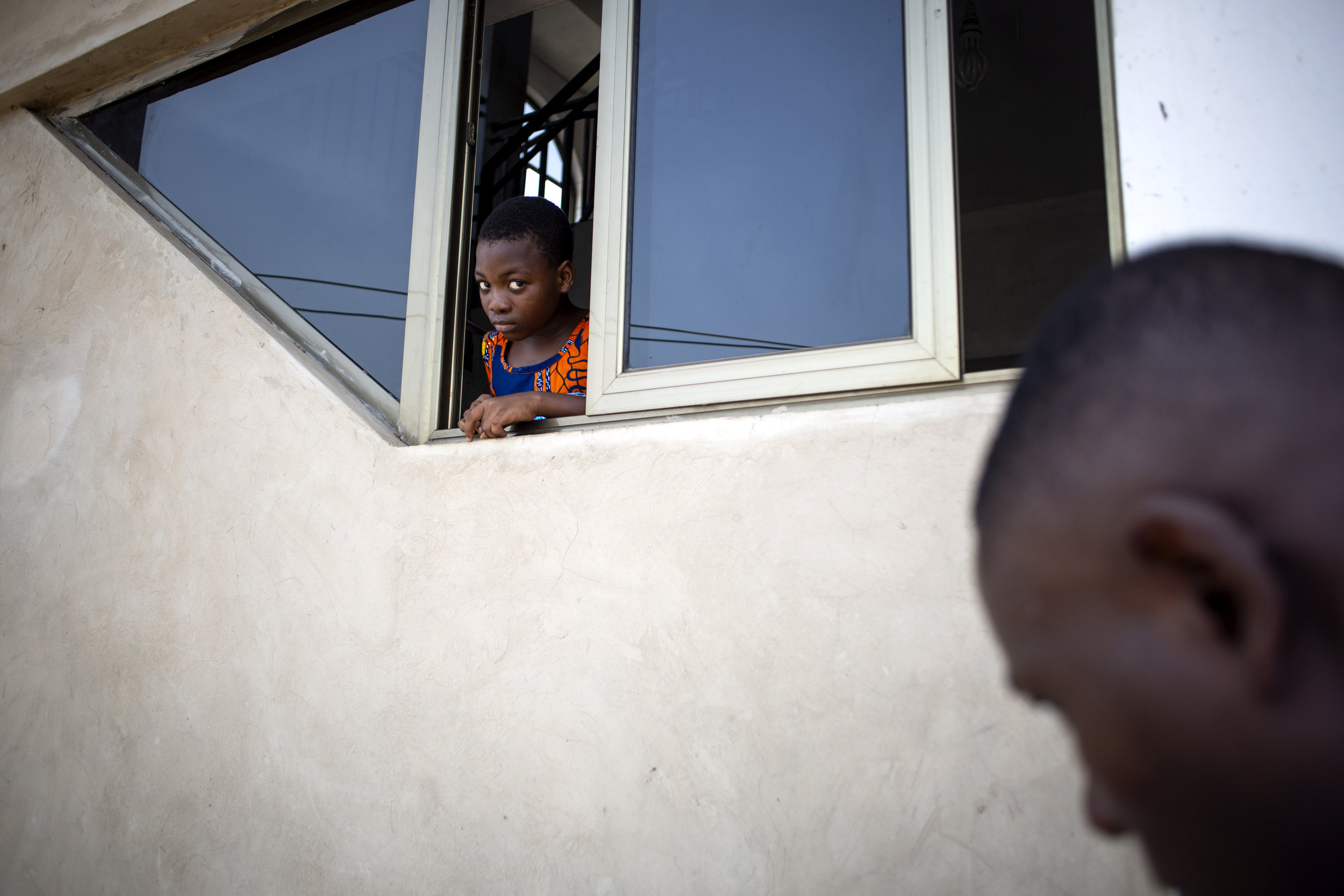  A young girl looks curiously out of a window during service at the S.D.A. Church in Maamobi, Ghana on March 25, 2017. 
