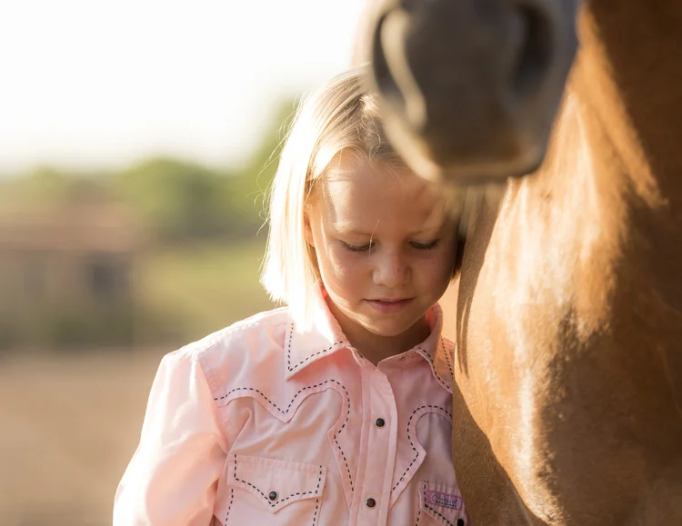 Ranching family with two young girls on horses in morning light at Cathedral Mountain Ranch, Alpine, Texas