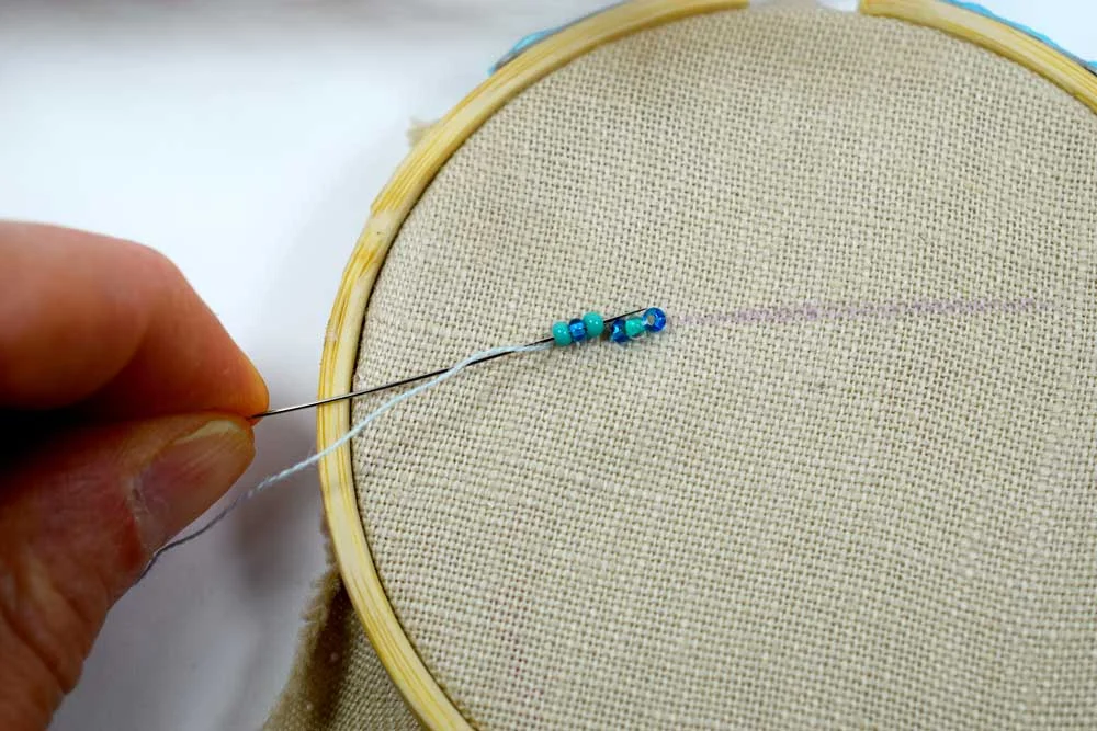 Sliding the needle through the first row of three beads.