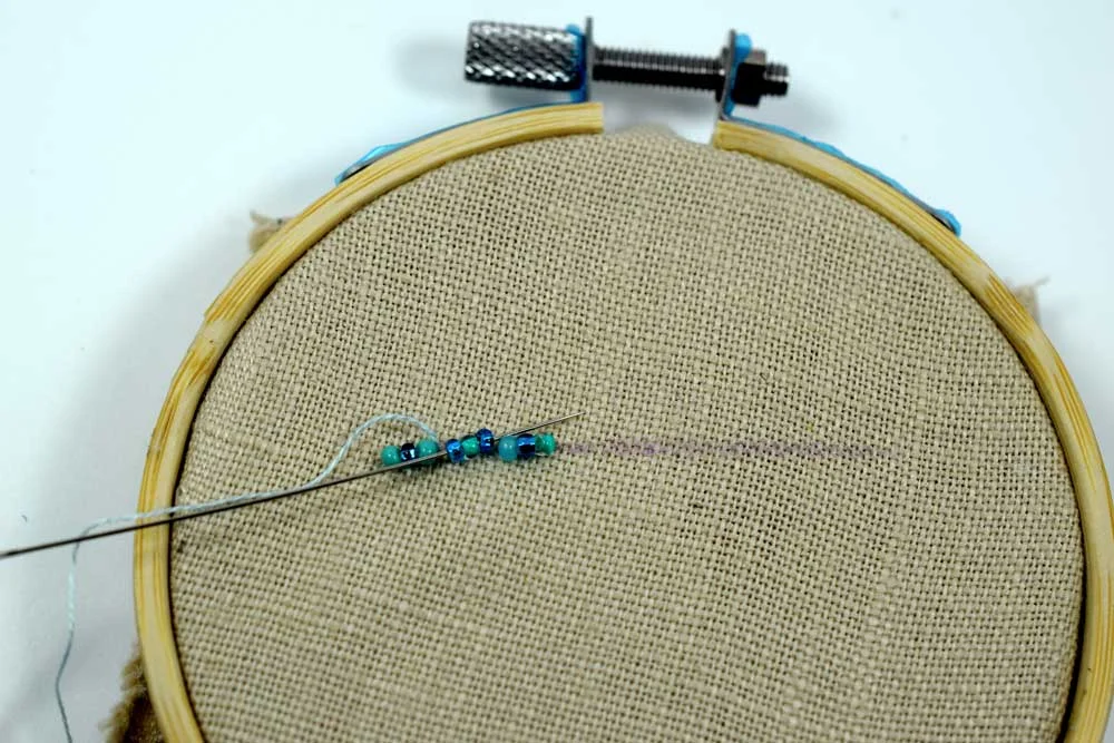 Running the needle through the second set of three beads.