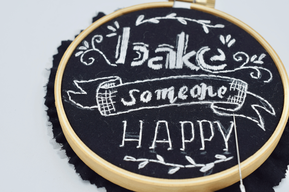 Once you are happy with your sketch, use your beginner stitch knowledge to sew over your sketch. In the above example, I used SATIN STITCH for the “bake” lettering, BACKSTITCH for the banner and “happy” lettering, and some LAZY DAISY for the petals. Simple. You don’t have to completely cover the white pen. It adds a more chalk-like effect to leave a little showing.