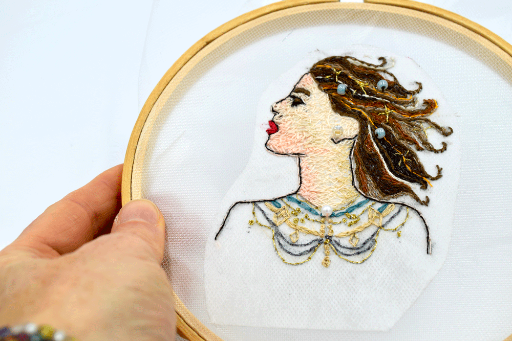 I stitched the design but instead of doing just the outline of the pattern, I filled in the face and hair. I also added some beads. Filling it in hides the stitch work in the back.