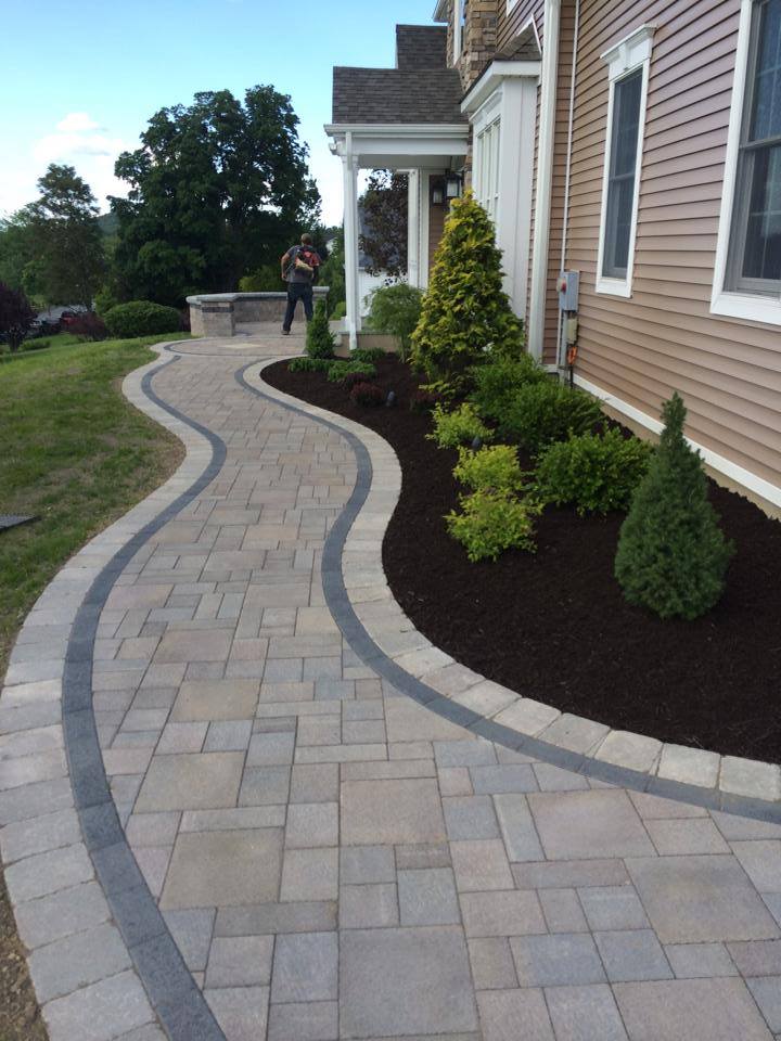The Landworx team putting the finishing touches on a sweeping, graceful front entrance built using Unilock products. 
