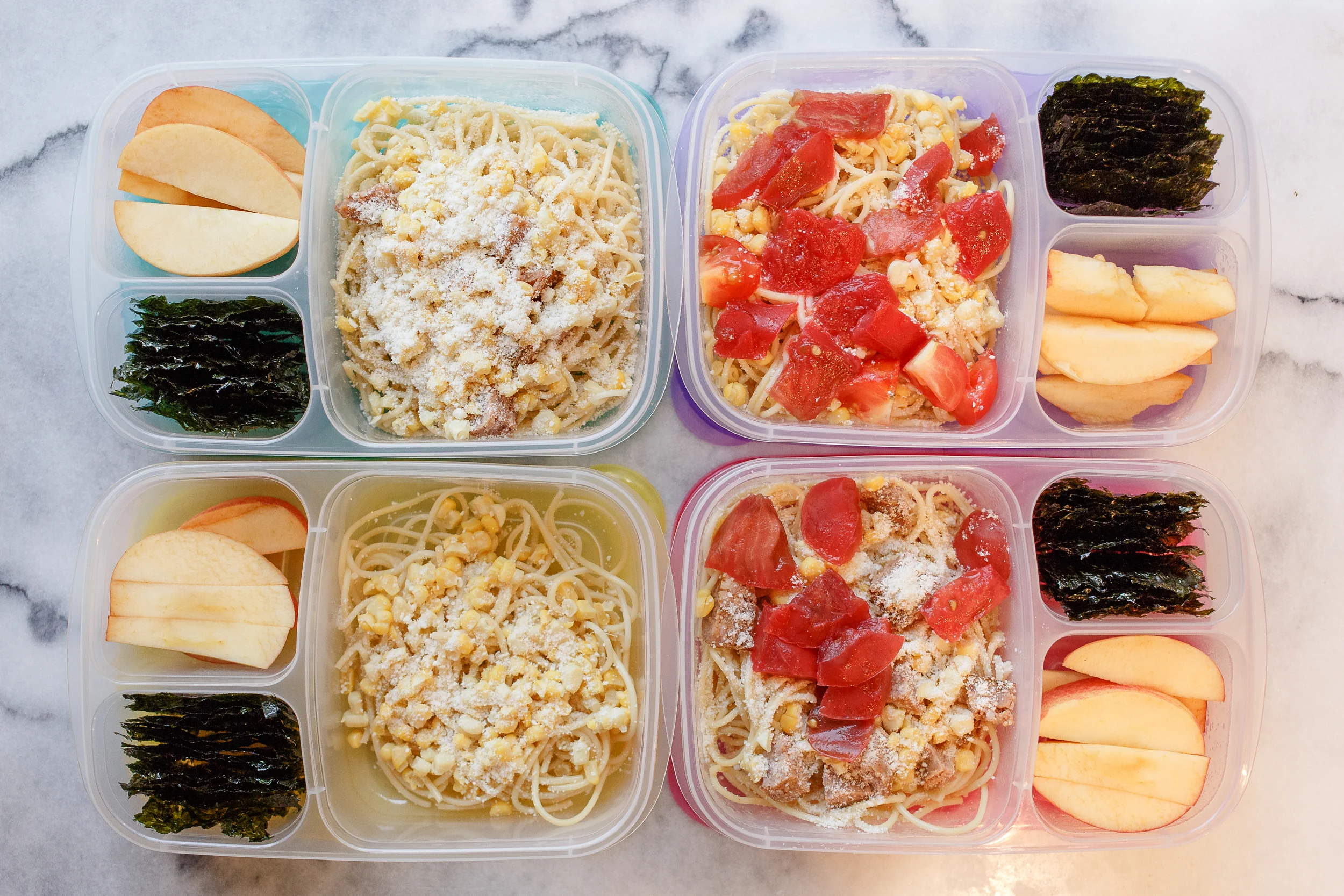 Leftover spaghetti with corn and cheese. One has tomatoes and sausage in it, one has just tomatoes, one has just sausage. Plus apples and seaweed snacks. 