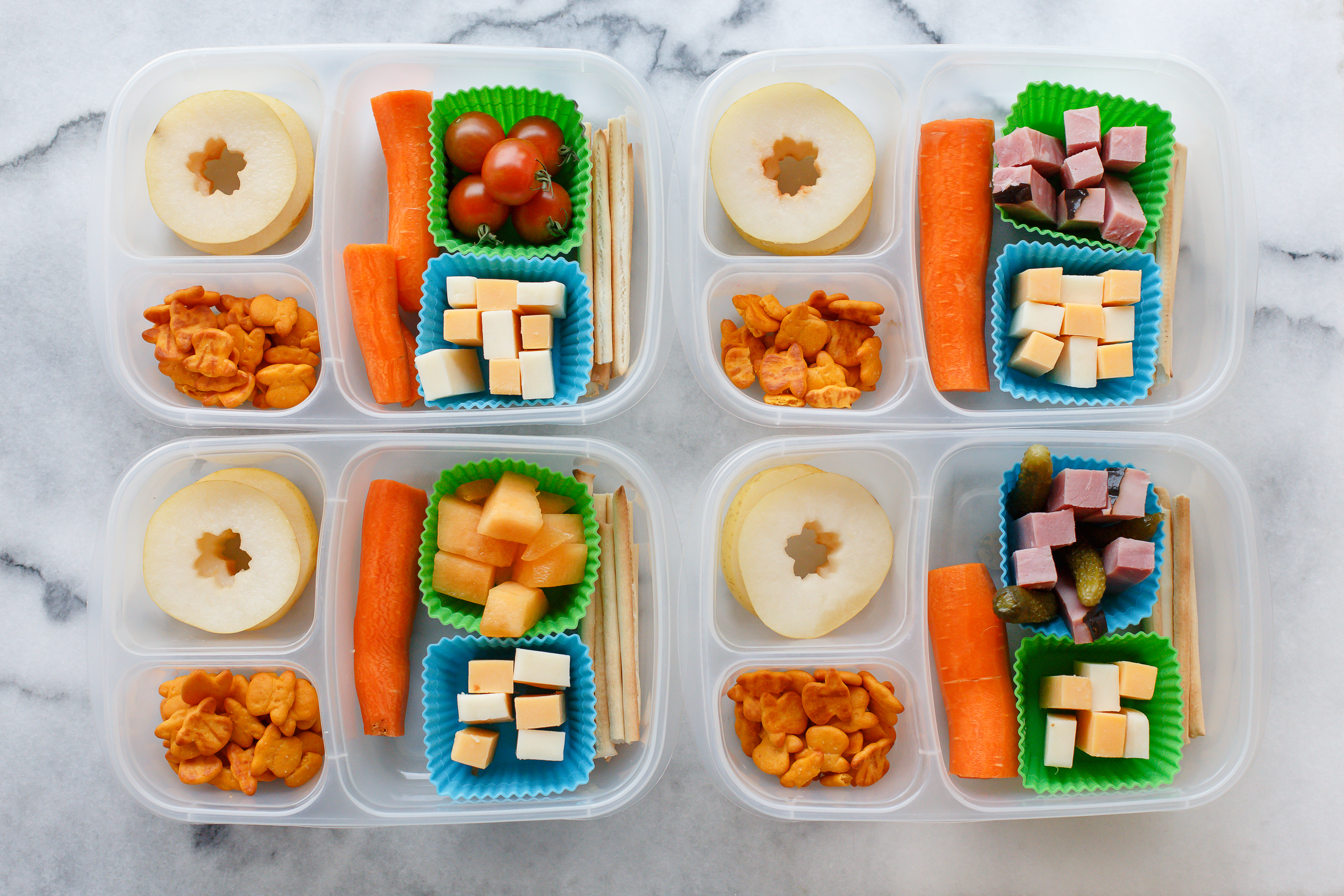 Tuesday lunch: sticks of cheese and ham. One has pickles, one has melon, one has tomatoes from the garden. With a big carrot, cheddar cows, and slices of pear. 