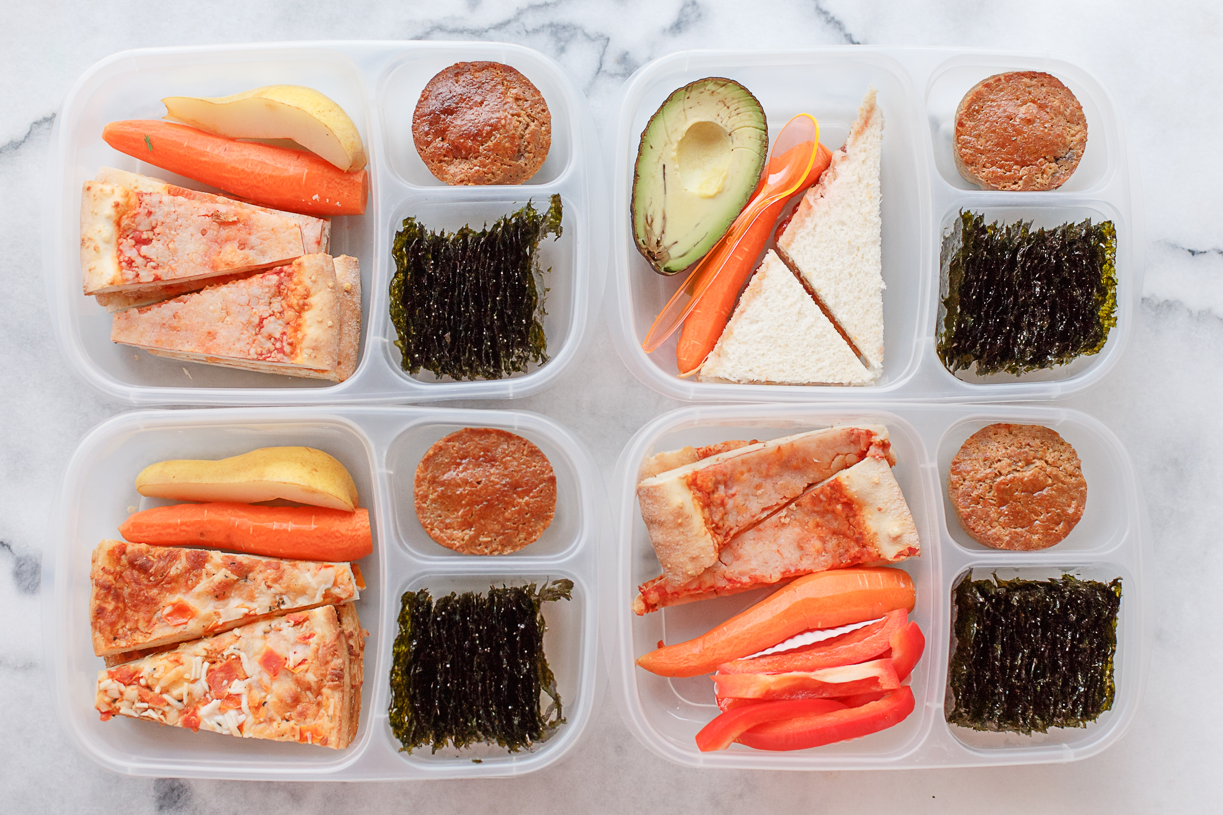 Monday Kid lunches: Three have leftover pizza from the weekend, one has quesadilla and avocado. They all have a carrot, seaweed snacks, and a homemade wheat blueberry muffin. Two have a piece of pear, and one has sweet red peppers. 