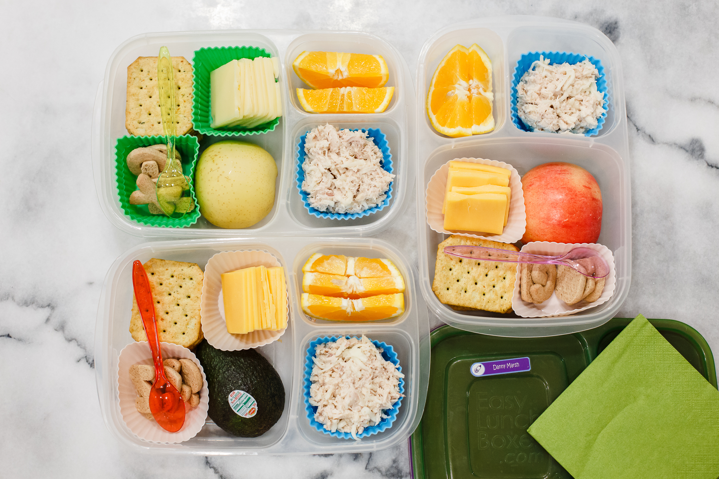 Thursday, lunches just for three: tuna salad, crackers, cheese, oranges and letter cookies. And one has half an apple, one has half an avocado, one has half a pear. 