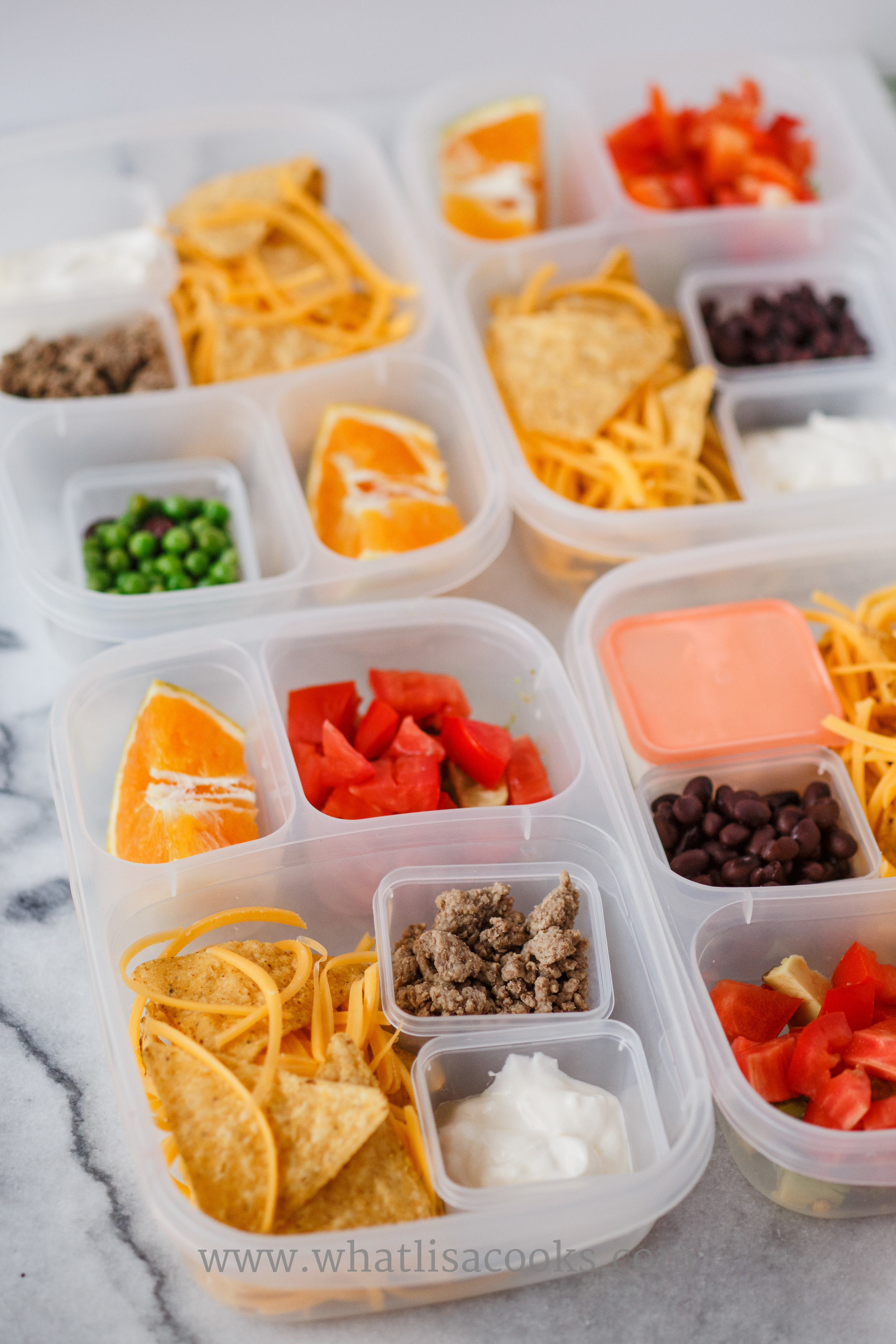 Nacho kits: tortilla chips, shredded cheese, meat or beans, sour cream. Three have tomatoes and avocados with lime juice, one has black beans and peas. 