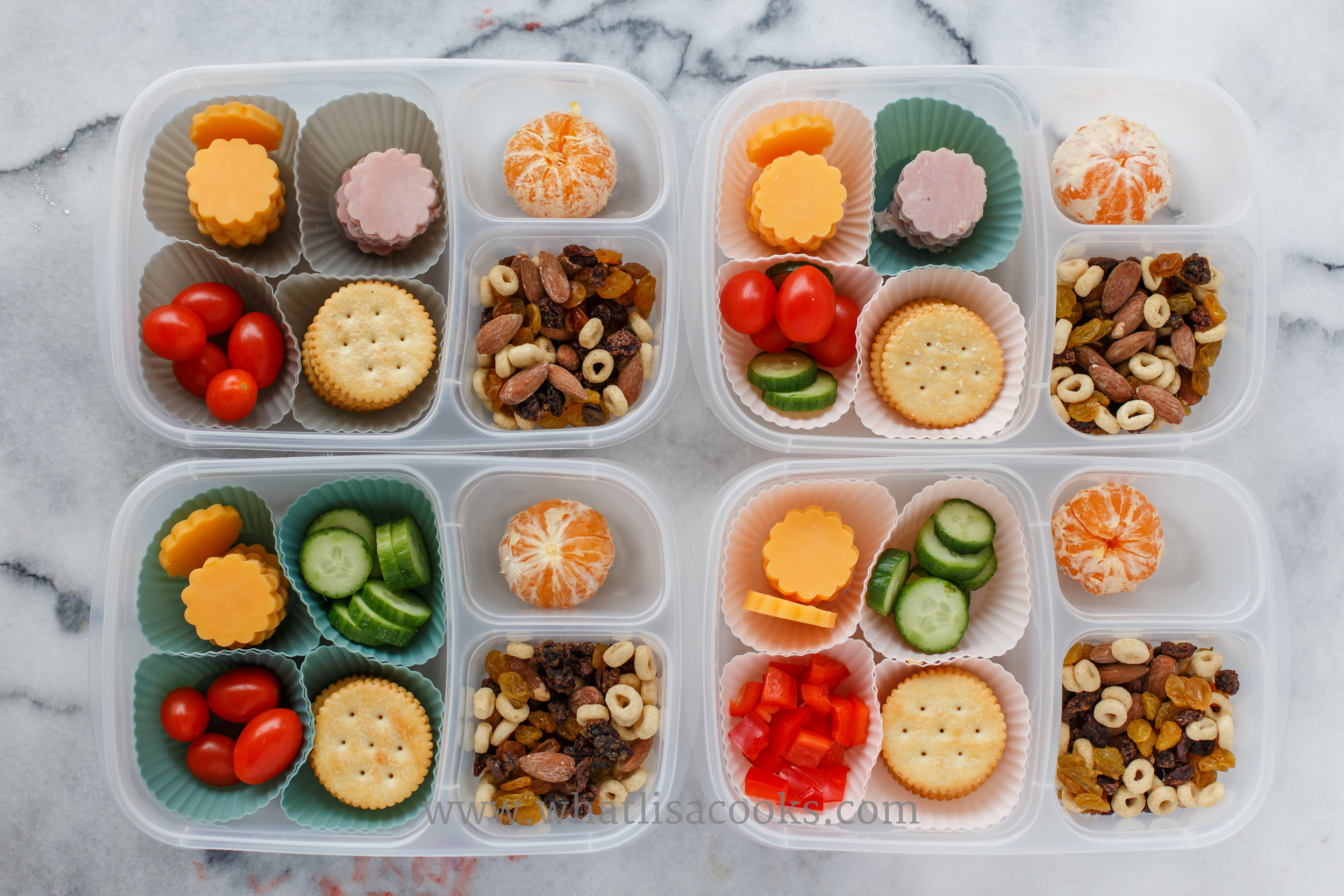 Lunchable: crackers, cheese, tomatoes, orange, two have ham, two have cucumbers, one has peppers, and they have a little trail mix on the side of almonds, raisins, and cheerios. 