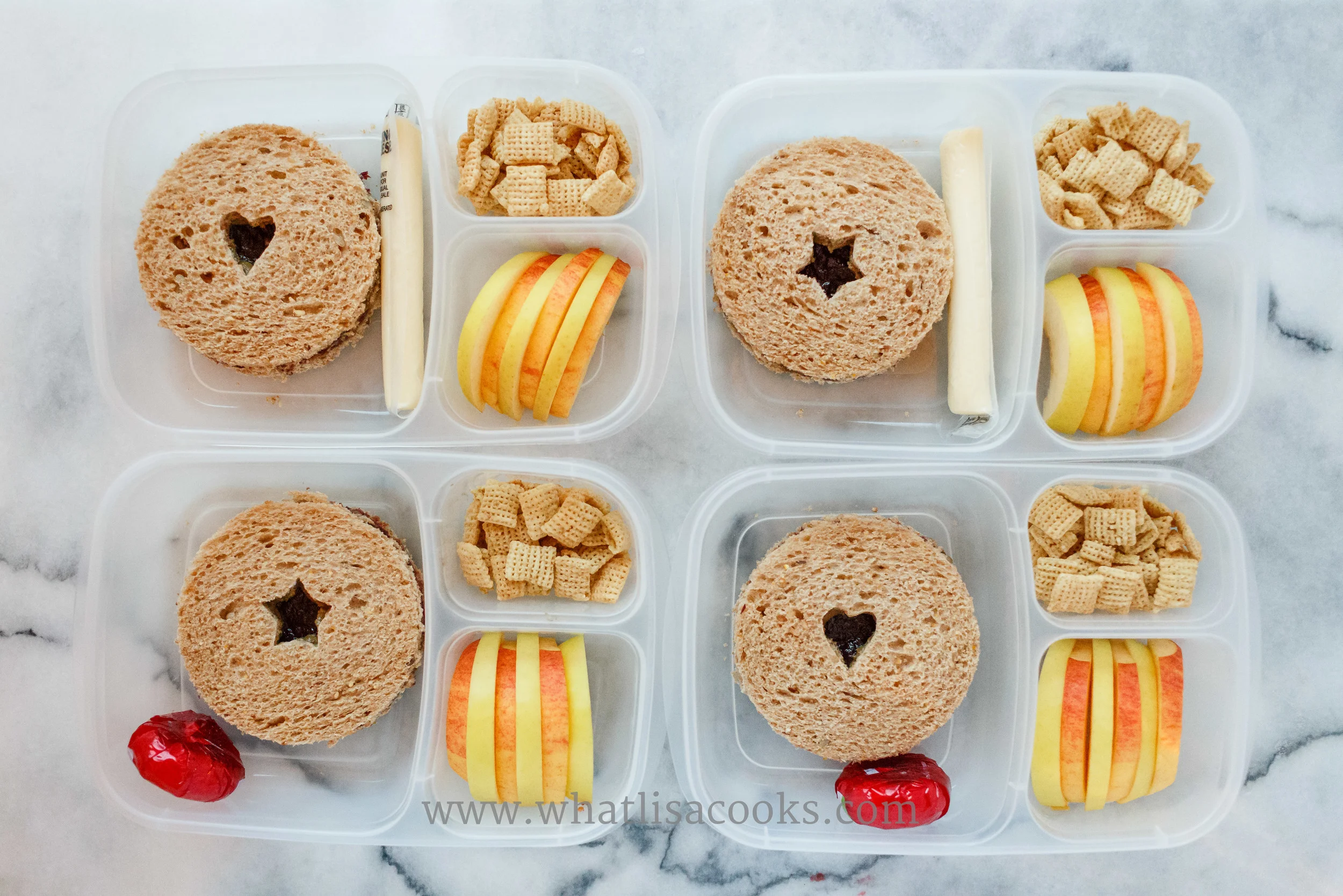 Simple sunbutter and jam sandwiches on multigrain bread, cheese, chex, and two kinds of apples just sliced and alternated.