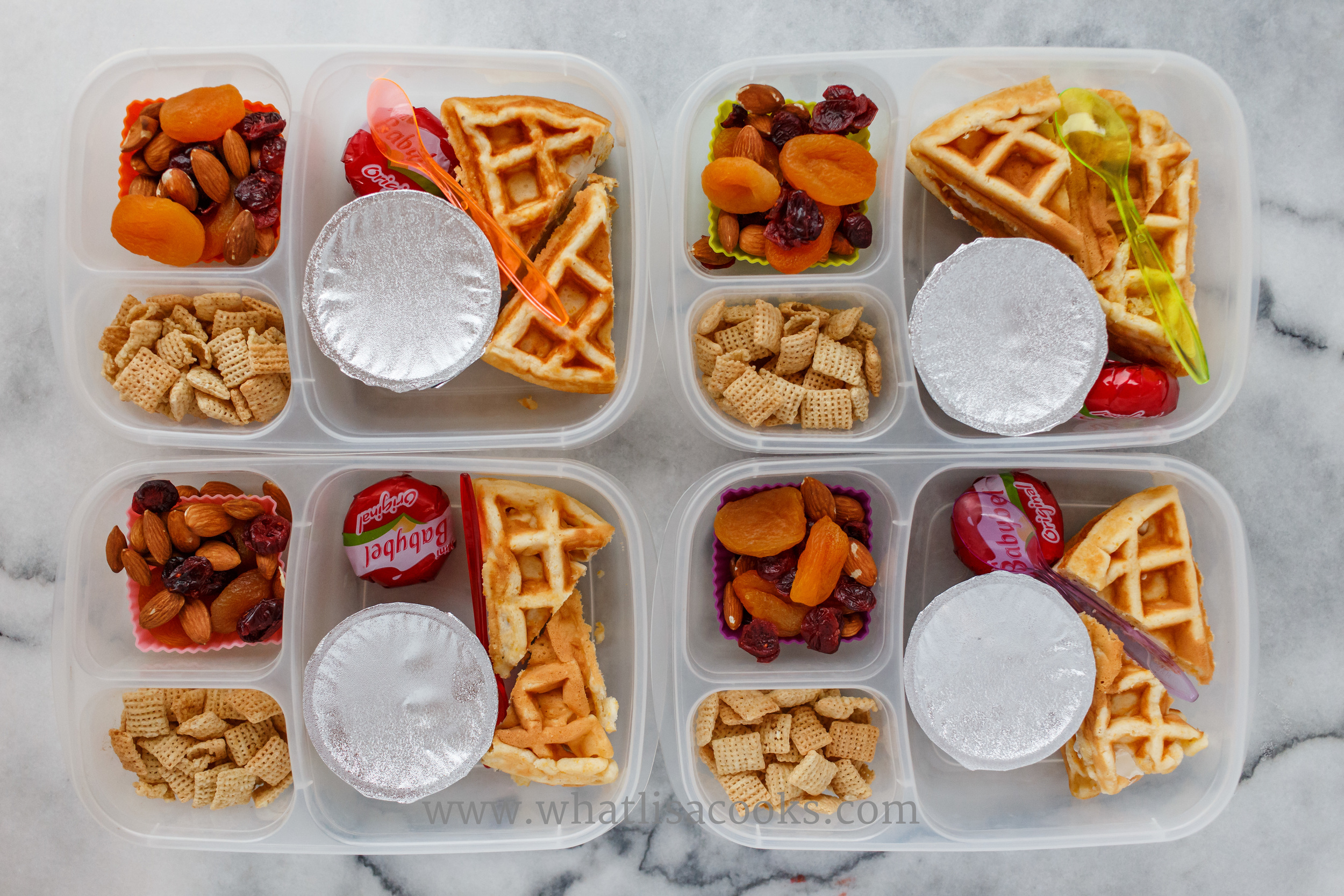Waffle sandwiches - three have cream cheese and one has butter; with cheese, applesauce, chex, and a trail mix of almonds, raisins, cranberries, apricots. 