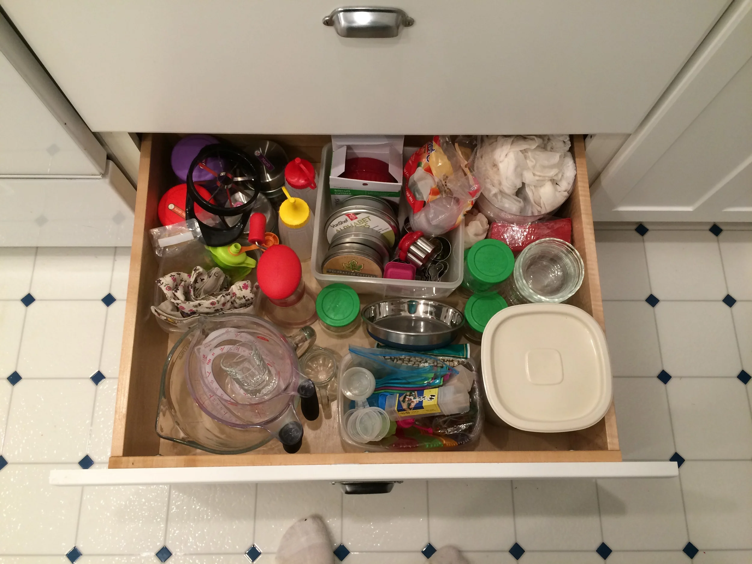 I have two big drawers to the right of the stove. The bottom one has a variety of things - lunch supplies, measuring cups, a few bowls, and the container of cat food (so the kids can easily feed the cats themselves). 