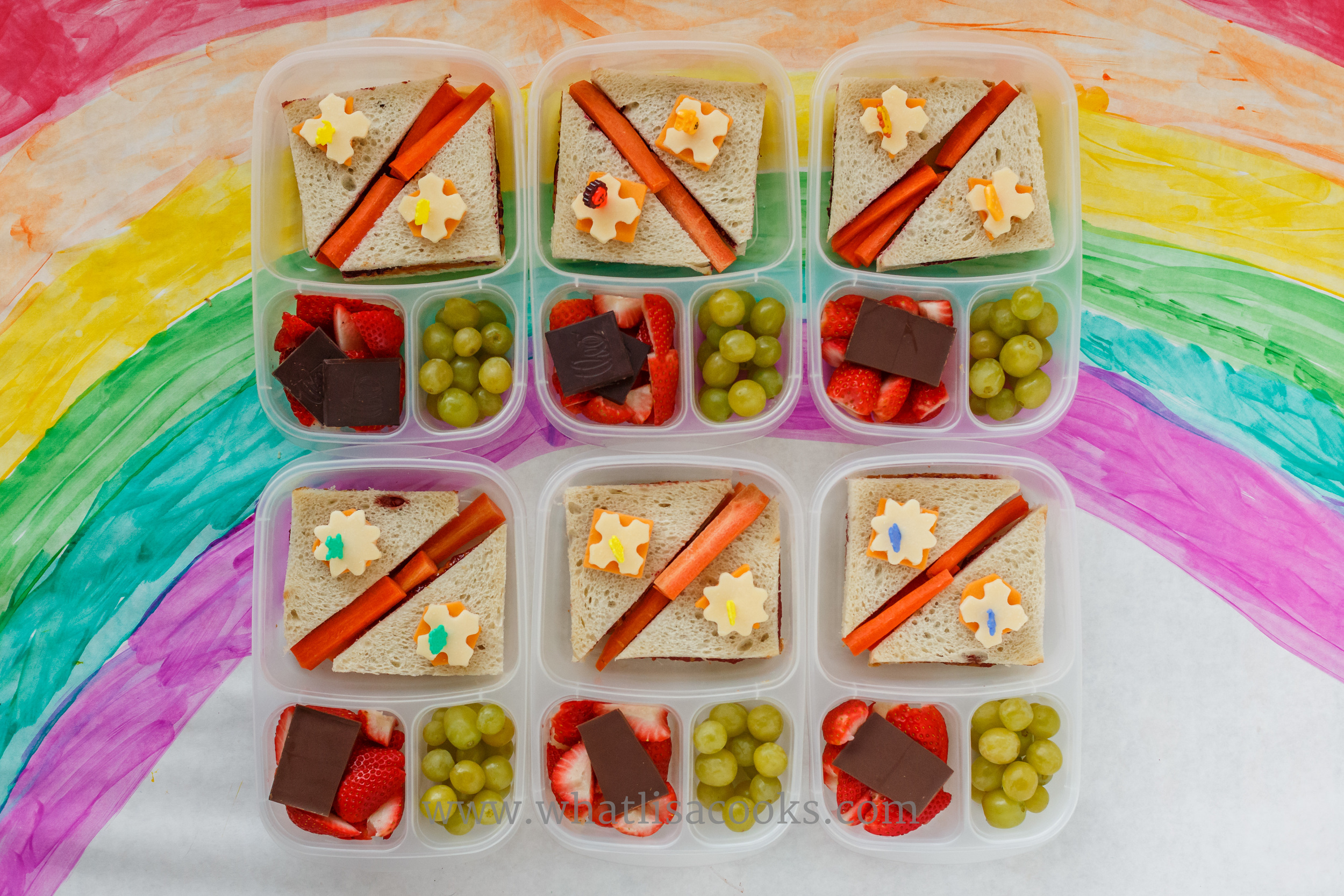 Saturday ski lunches for 6: PB&J. Good white bread from a local bakery (no mystery ingredients!), Trader Joe's peanut butter (ingredients: peanuts, salt), and homemade jam (four have strawberry, two have blackberry). Cheese cutouts on top, carrots in the middle, on the side there are grapes, strawberries, and chocolate. 