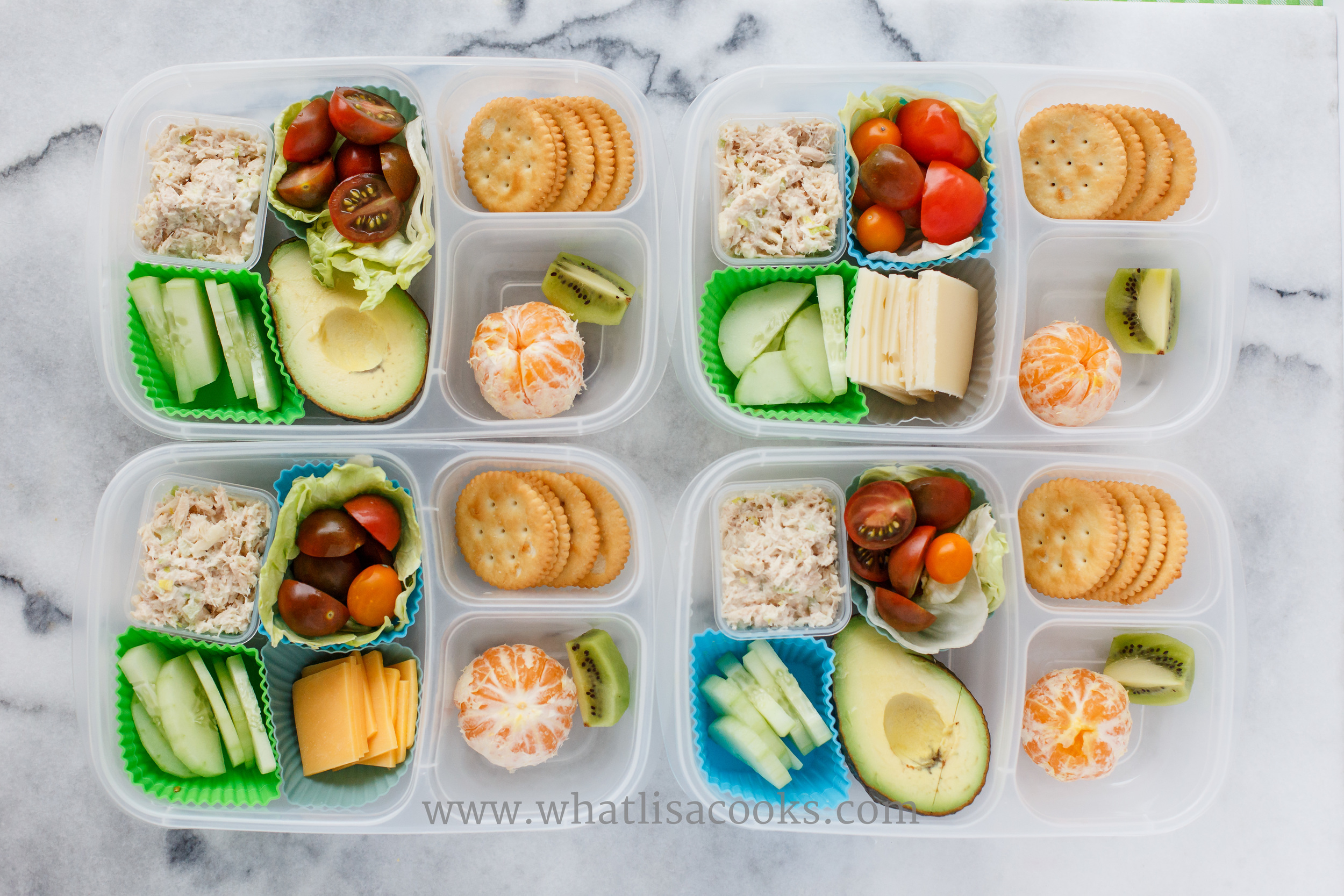 Chicken salad, cucumbers, tomatoes, orange and kiwi. Two have avocado, two have cheese. Serve with gluten free crackers. 