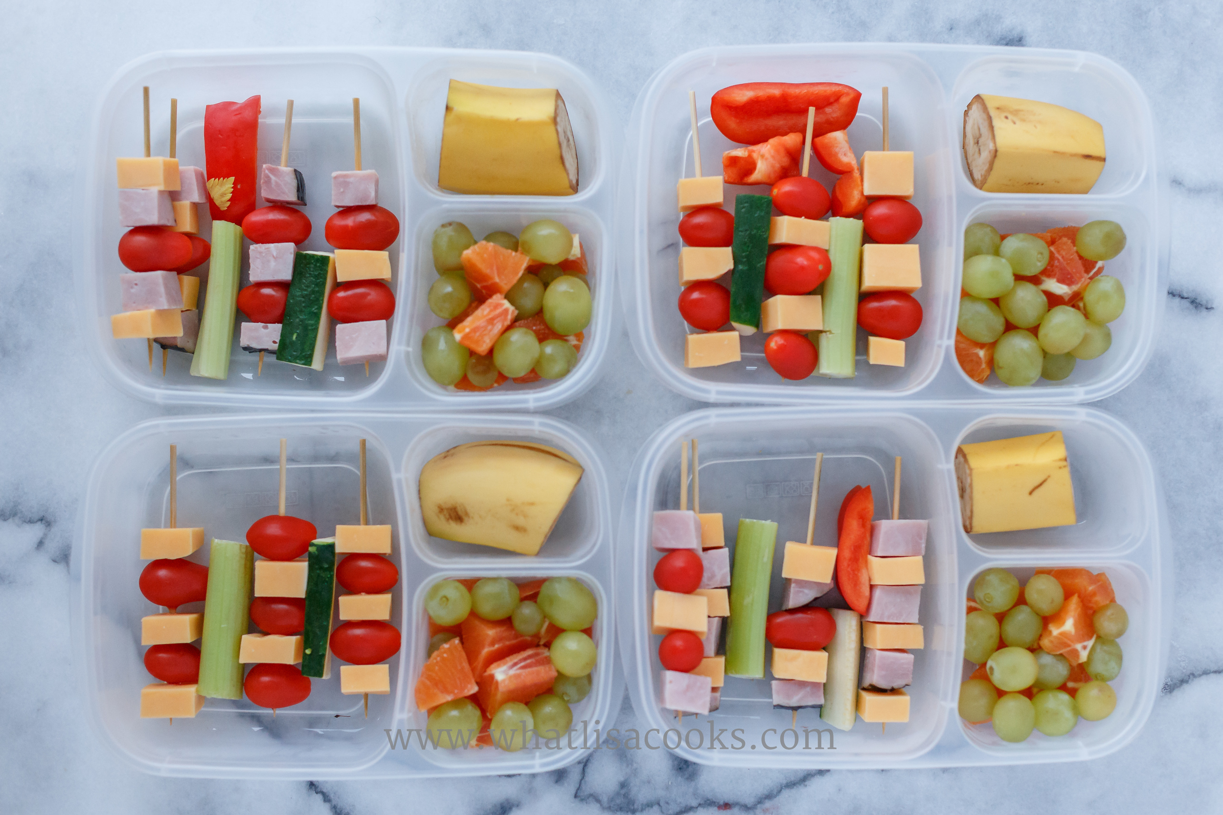 A grain free lunch. Skewers of tomatoes, cheese, and ham for the two that eat it. In between they each have a piece of zucchini, celery, and red pepper (which they did taste!). Fruit on the side: banana, grapes, oranges. 