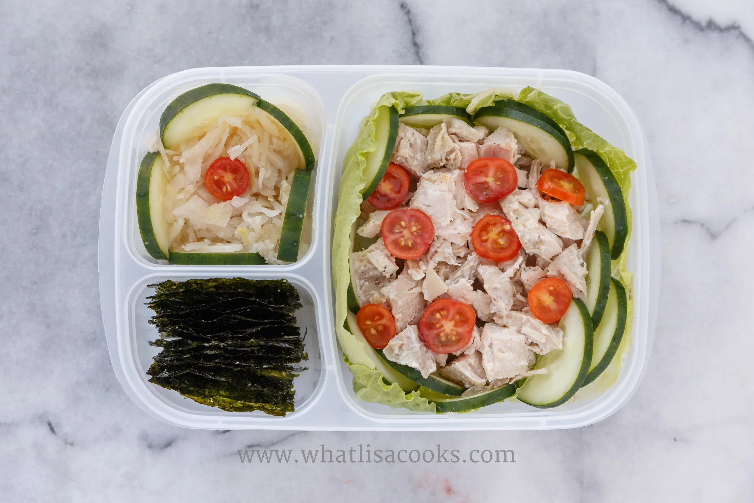 A simple chicken salad, with just roasted chicken, mayo, seasoned salt, on top of lettuce, with cucumbers and tomatoes. One the side there is raw fermented sauerkraut, and some seaweed. (this is my lunch, not a kids lunch).