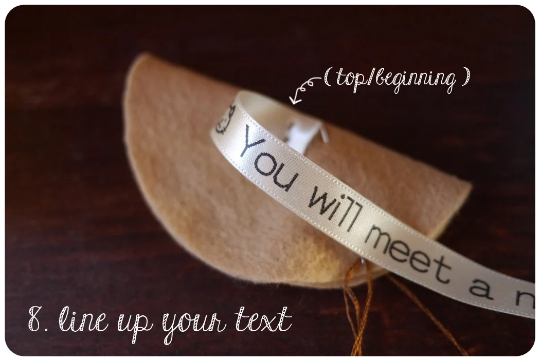 Line up the ribbon with the fold of the fortune cookie (the top of the ribbon should line up with the edge of the half circle, with the beginning of the ribbon closest to the stitched line). The beginning of the ribbon should overlap the line slightly.
