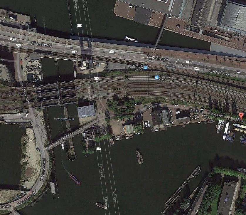 Kop Dijksgracht. De klimmuur aan de Oosterdoksdoorgang blijft gehandhaafd. Aan de Dijksgracht komen/blijven van links naar rechts: Hannekes Boom, toekomstige ligplaats horecaschip Barco, toekomstige Shaffy's tuin (zelfbeheer), vm. DIVV-werf wordt Mediamatic broedplaats, locatie tijdelijke brug naar Marineterrein,