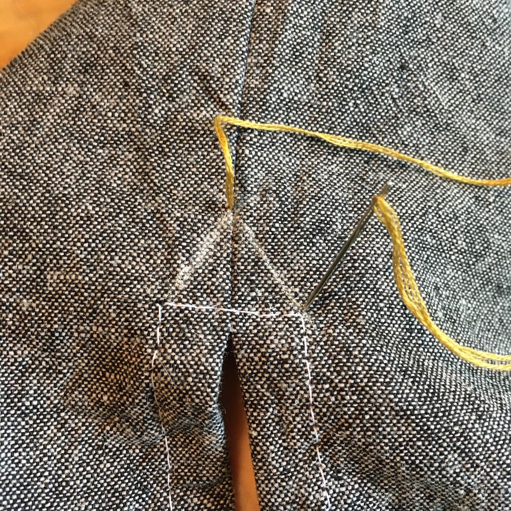 First, draw in your little triangle as a guideline. With a strand of embroidery floss, pearl cotton or buttonhole thread, come up through the top of the triangle, then down through one bottom corner.