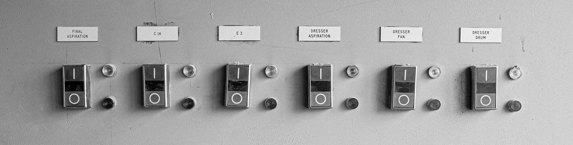 Switches with labels such as 'Final Aspiration', 'C 14', 'E 3', 'Dresser Aspiration', 'Dresser Fan', and 'Dresser Drum' on a gray wall.