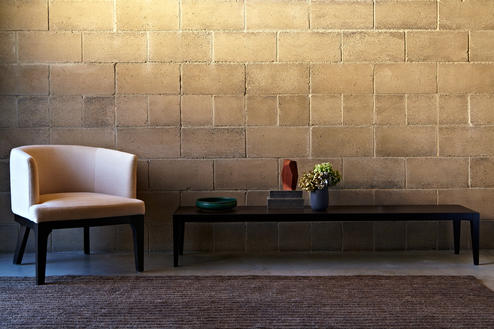 A soldier course of eight inch blocks with a white linen club chair and hand woven Odegard rug. Just as natural rock is made up of a million individual grains of quartz, feldspar, and trace elements, Watershed Blocks celebrate their unique composition. Unlike uniform concrete blocks, made of cement and dye, no two Watershed Blocks are exactly the same. Find out more at the Watershed Materials website.