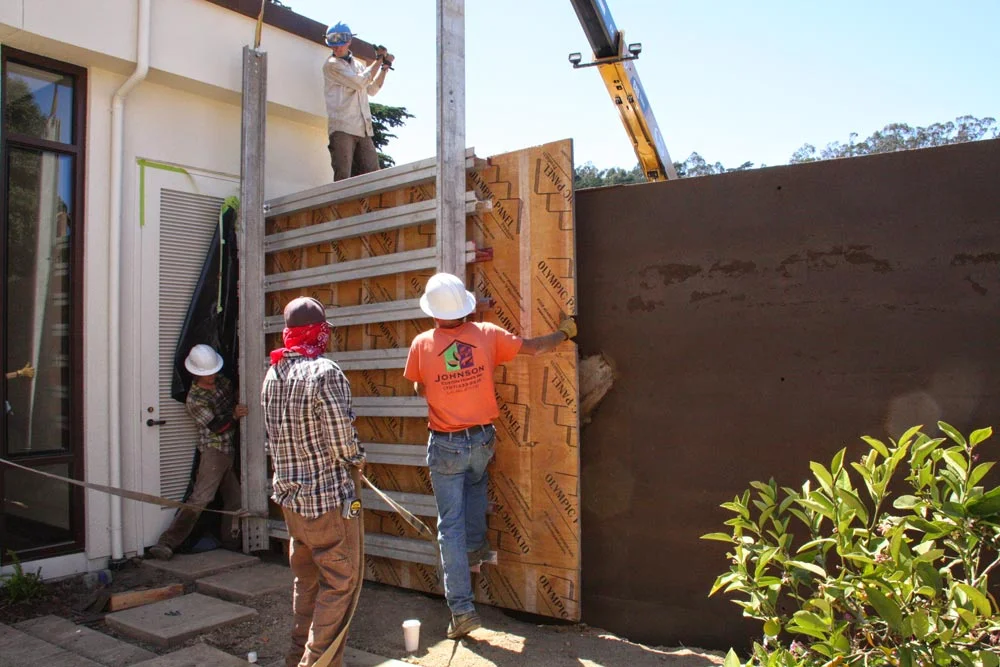 Formwork is removed revealing a freshly packed rammed earth wall and the center point of the ball of gnarled eucalyptus branches. Both the raw earth for the rammed earth wall and the eucalyptus wood was sourced from the surrounding Presidio.