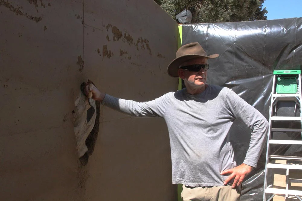 Artist Andy Goldsworthy poses with the installation before beginning to dig out the earth surrounding the encased eucalyptus wood.