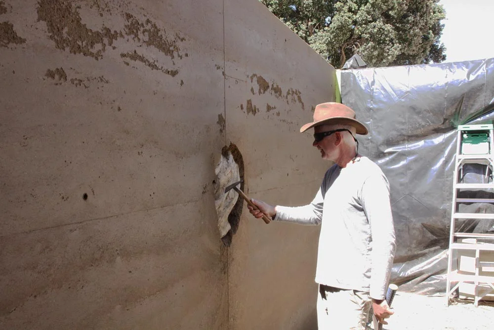 Artist Andy Goldsworthy poses with the installation before beginning to dig out the earth surrounding the encased eucalyptus wood.