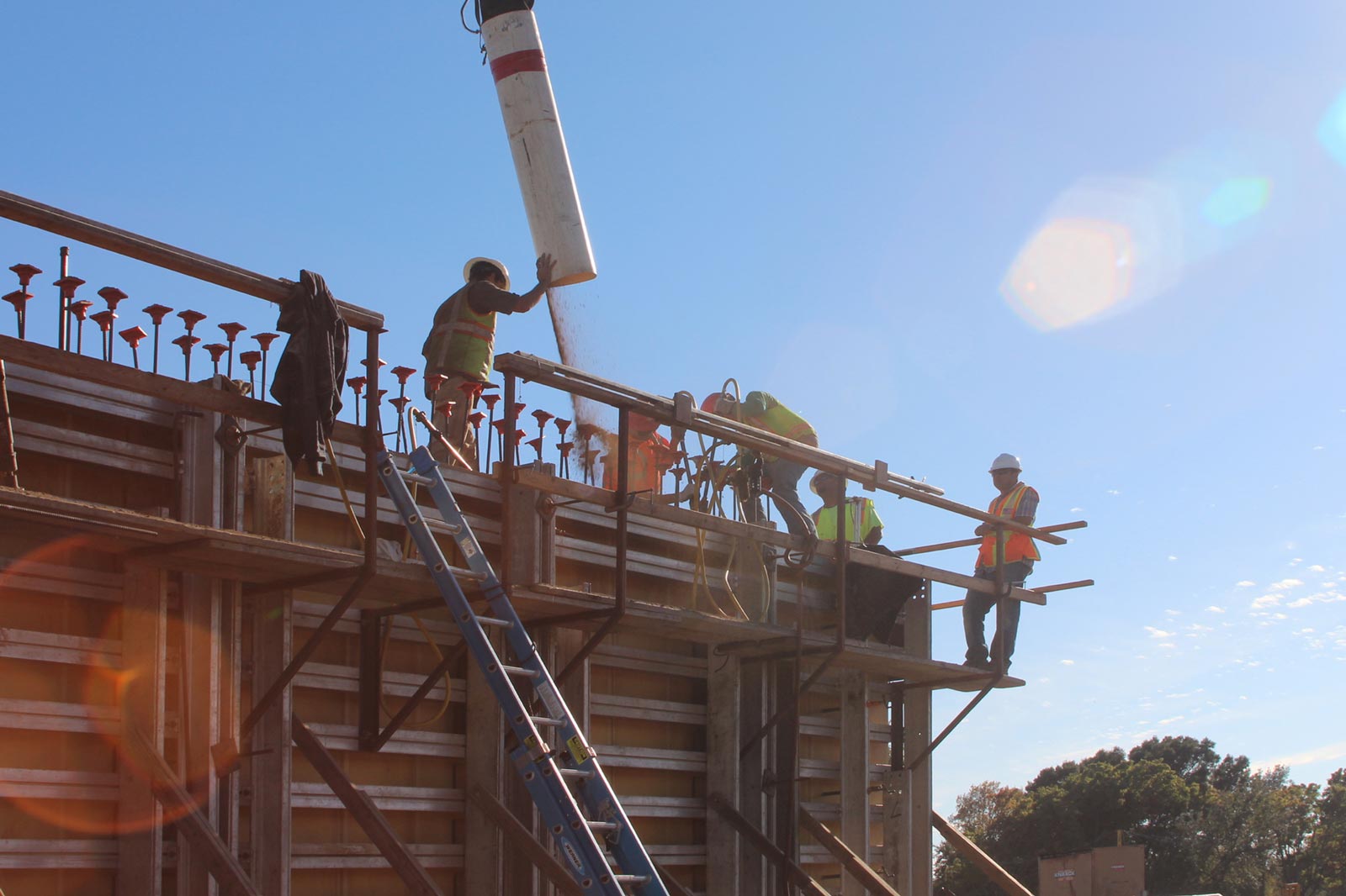 Rammed earth differs from concrete in that the mixture is delivered to the formwork in six inch layers, each of which is compacted (rammed) to achieve the density that turns the earth back into the stone of its origin. Read more about the project’s development in our blog .