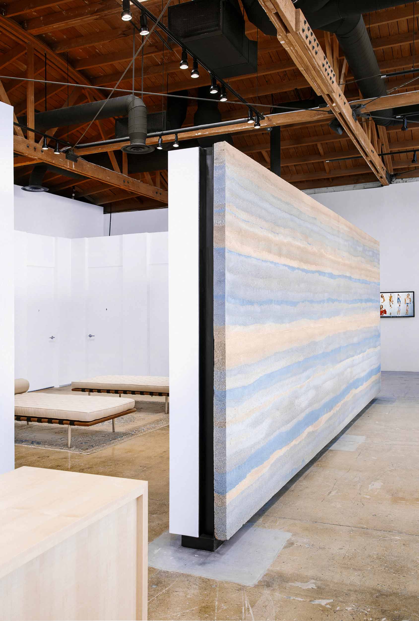 The Reformation wall of stratified rammed earth was cast in our Napa studio as two separate panels, each weighing roughly 5000 pounds. Like all rammed earth, the panels are built up in layers, which read as geologic strata. The degree to which each strata differs from the others is the product of the components in the mix design. Think of a mix design as a recipe in a cookbook, except rather than ingredients like milk, flour, sugar, eggs, and baking soda, our recipes use gravel, sand, clay, silt, and binder. Gravel will give a wall coarse texture, silt will impart a smooth, leather-like surface. Sand represents the greatest percentage and is used to give strength to the panel, and the mineralogy of the clay has the greatest effect on the color. We avoid using pigment dyes because the colors are muddied. Instead we scour the countryside and the quarries for crushed clay and soils that we can add to the mix so that the finished panels resemble the native rock from which ingredients are derived. Image © Jesse Gillan