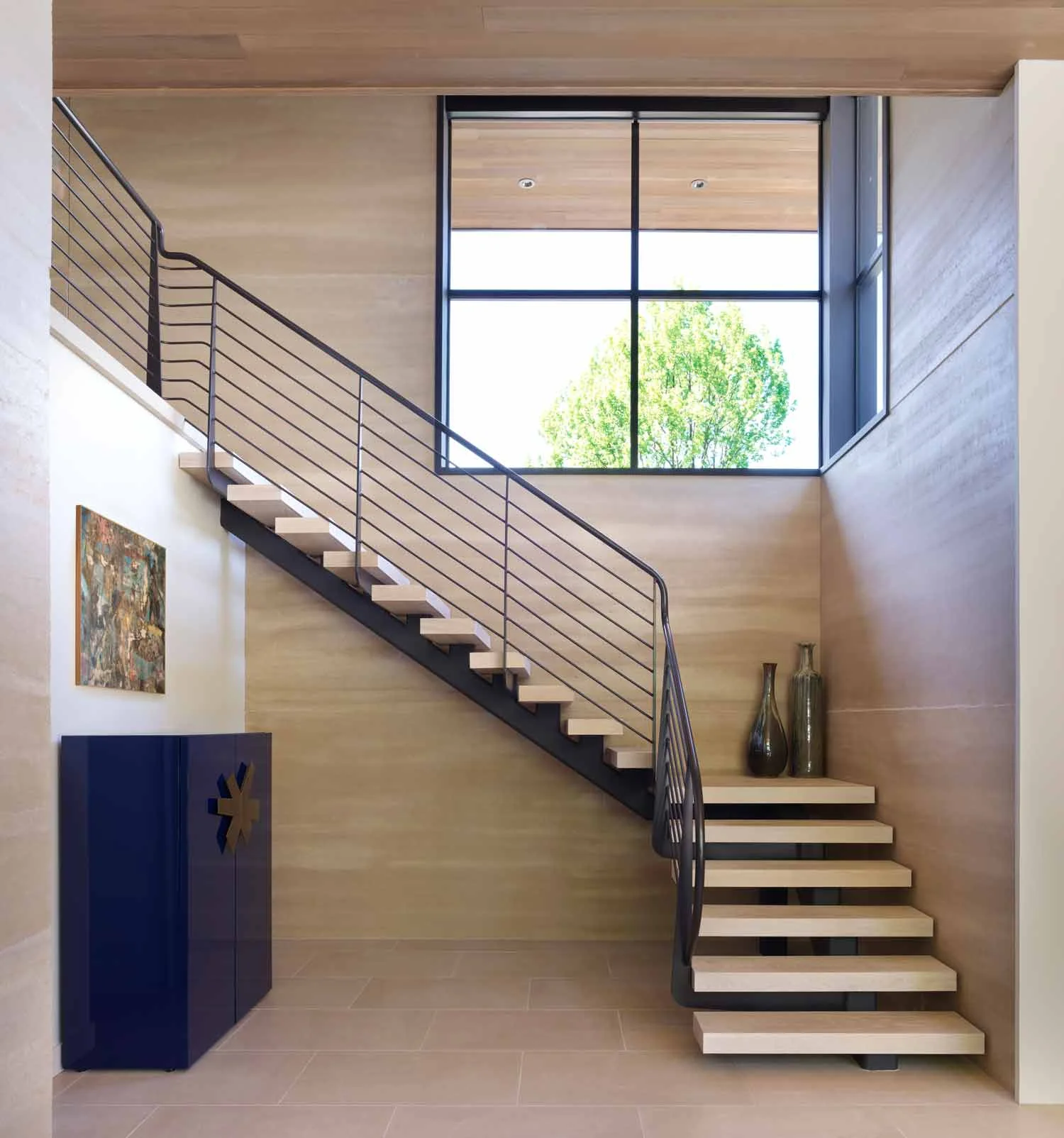 Architect Ana Williamson and builder Aurelio Peccei brought together the perfect combination of materials to highlight the intrinsic beauty of the rammed earth panels. In this interior view of the entry stairway, the limestone floor pavers and stair treads appear to be yet one more strata line in the walls. It takes four five foot tall panels stacked on top of each other to reach to the twenty foot plate height.