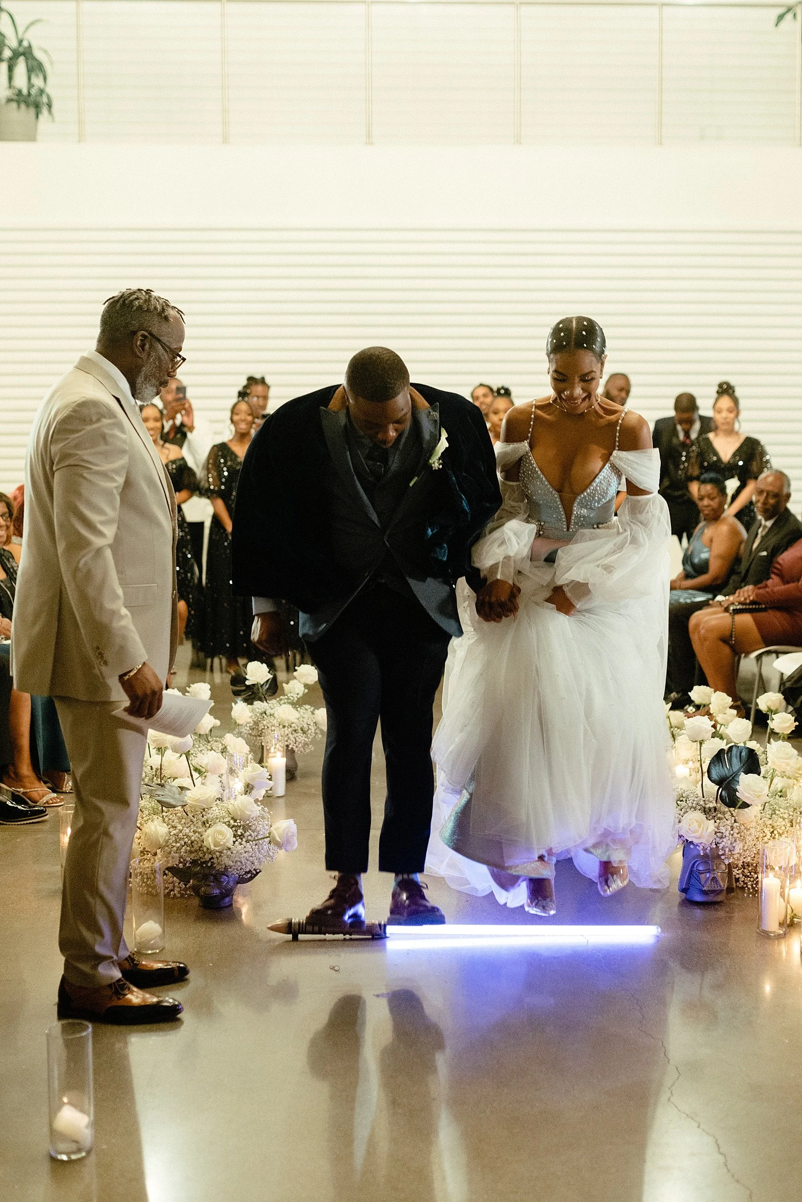 Nerdy black couple getting  married and jumping the broom over a lightsabre