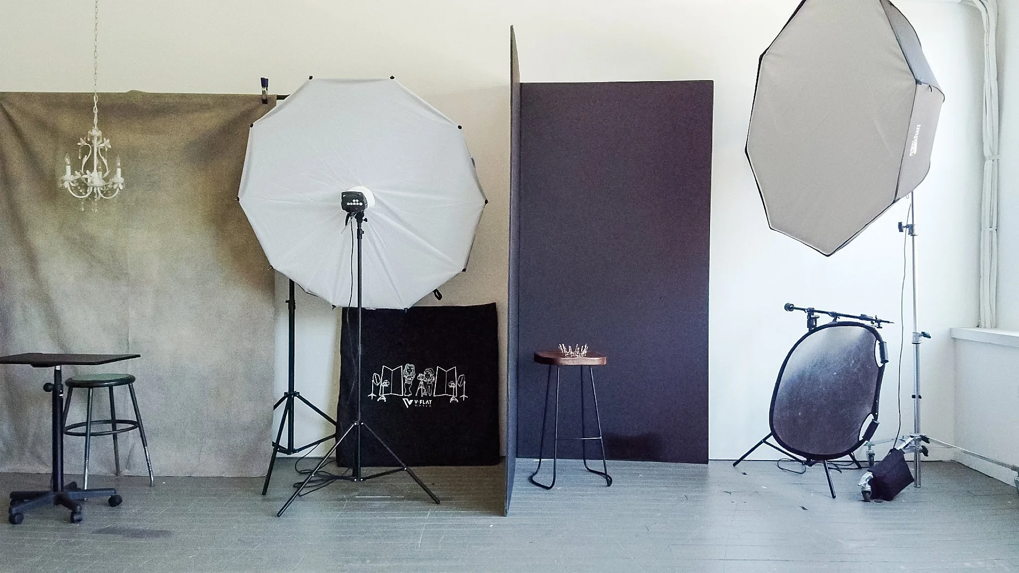 Photography studio setup with backdrop, lighting equipment, and a small stool