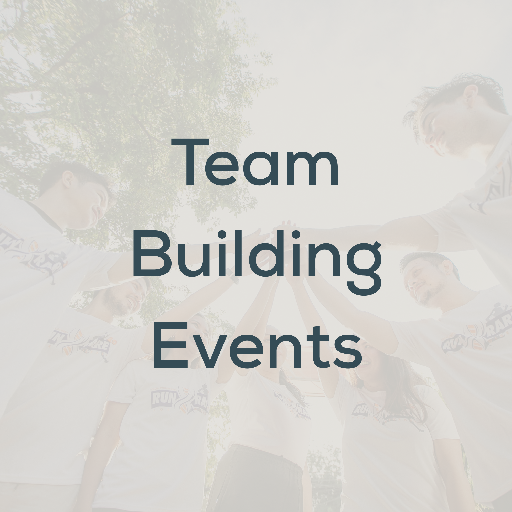 A group of people in sport jerseys standing in a circle outside, with their hands stacked together in the center, celebrating teamwork.