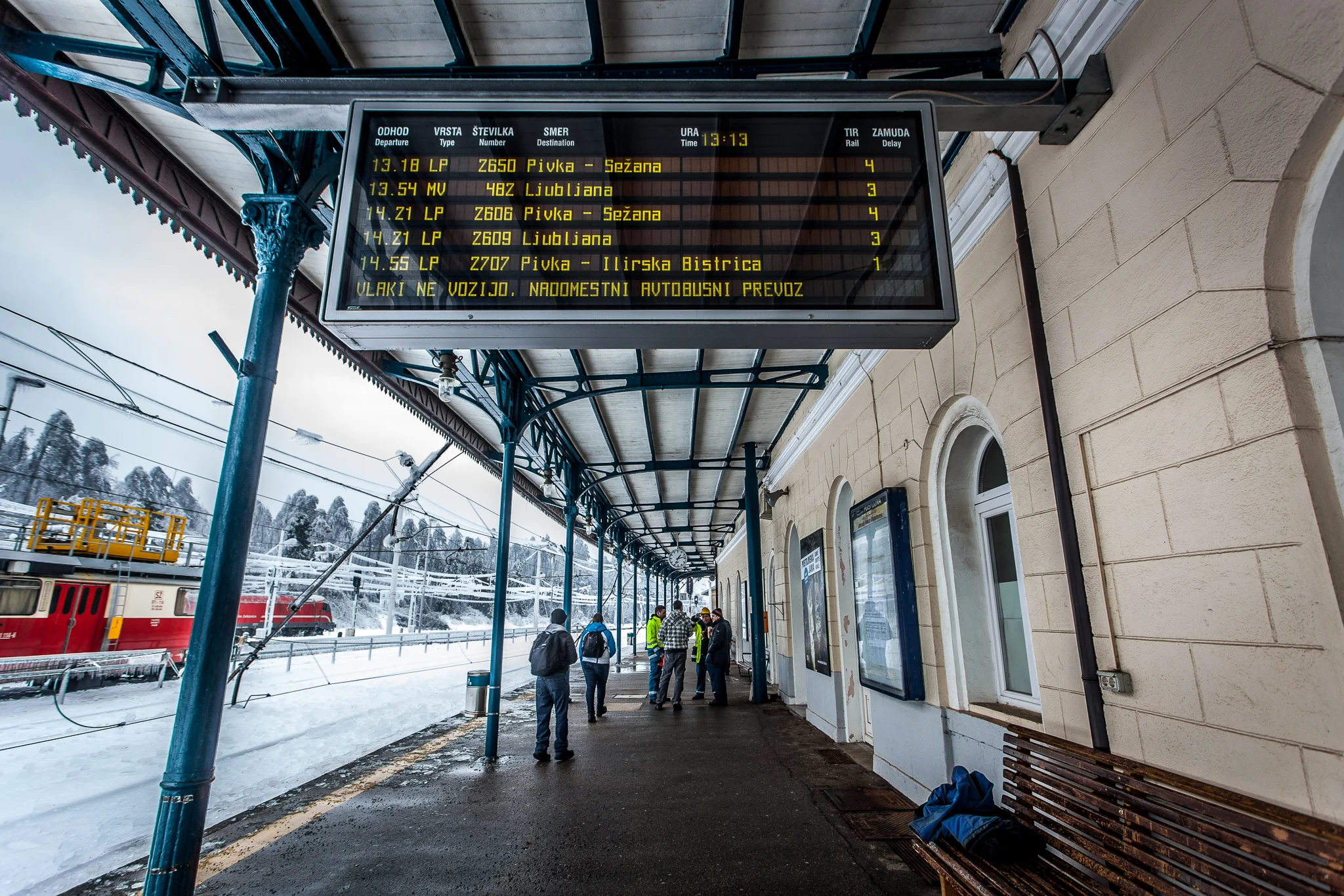 'Trains do not run. Substitute bus service' sign on the info-board at the Postojna train station. Workers are talking about repairing the tracks.