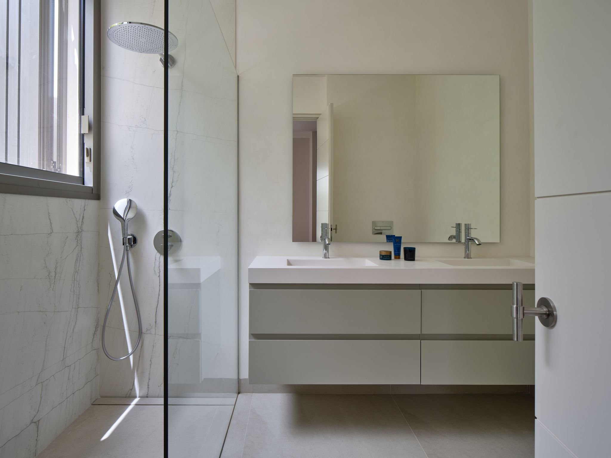 Modern bathroom with a glass shower, double sink vanity, and large mirror.