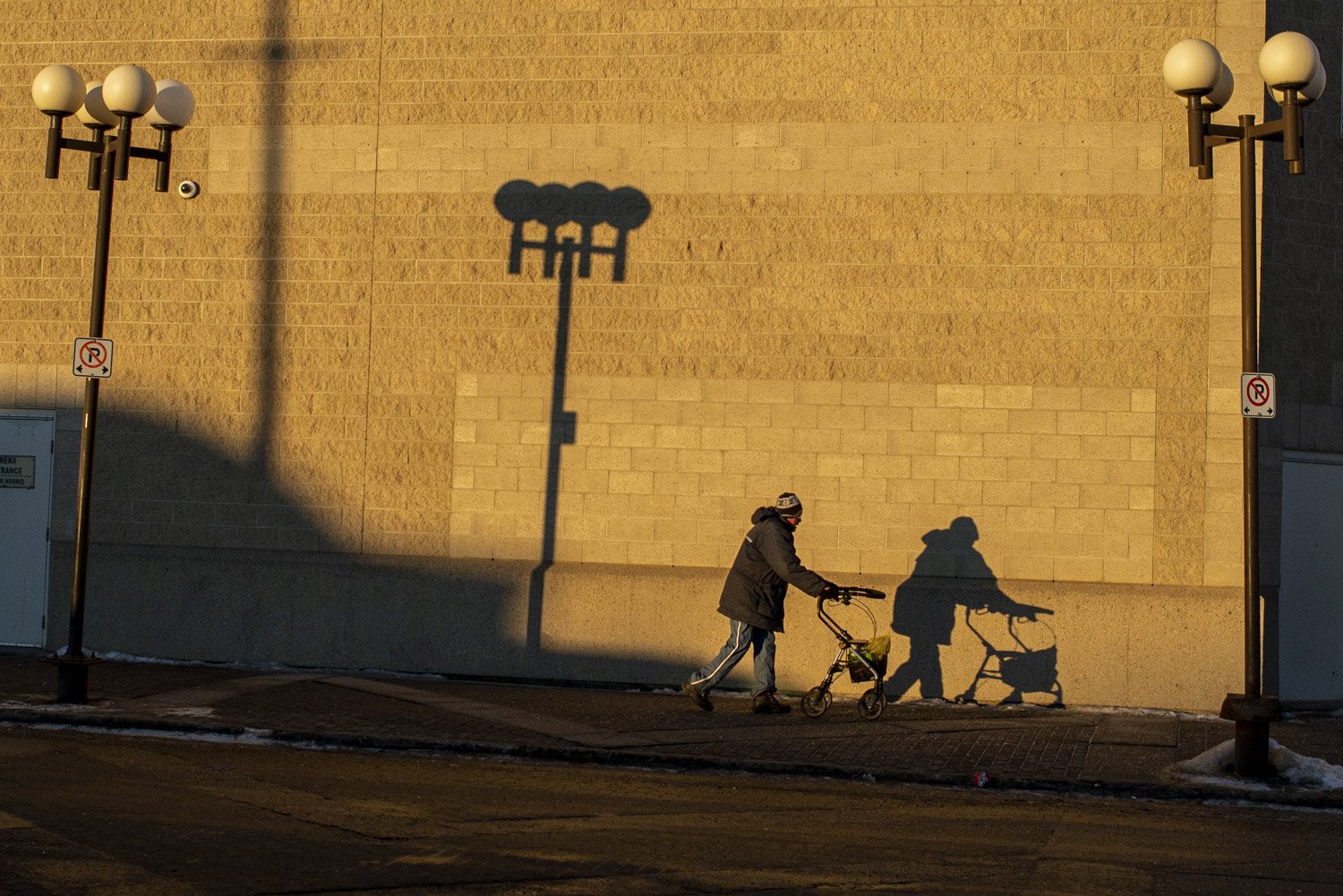  A man and his walker are silhouetted in the early morning light on the wall of a downtown building in Grande Prairie, Alberta.  La silhouette d’un homme et sa marchette est projetée sur un mur en brique tôt le matin dans le centre-ville de Grande Pr