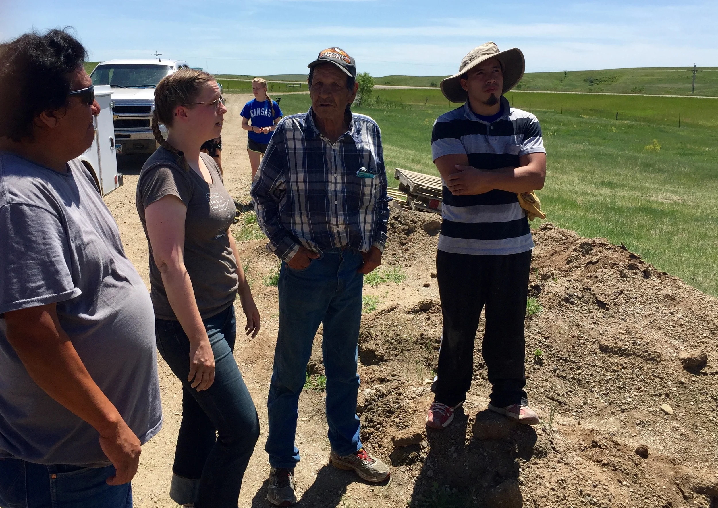 Plymouth Leader Eleanor (second from left) speaks with the housing recipients - Kee, Ford, and Elvis - at the housing site of Ford (second from right).
