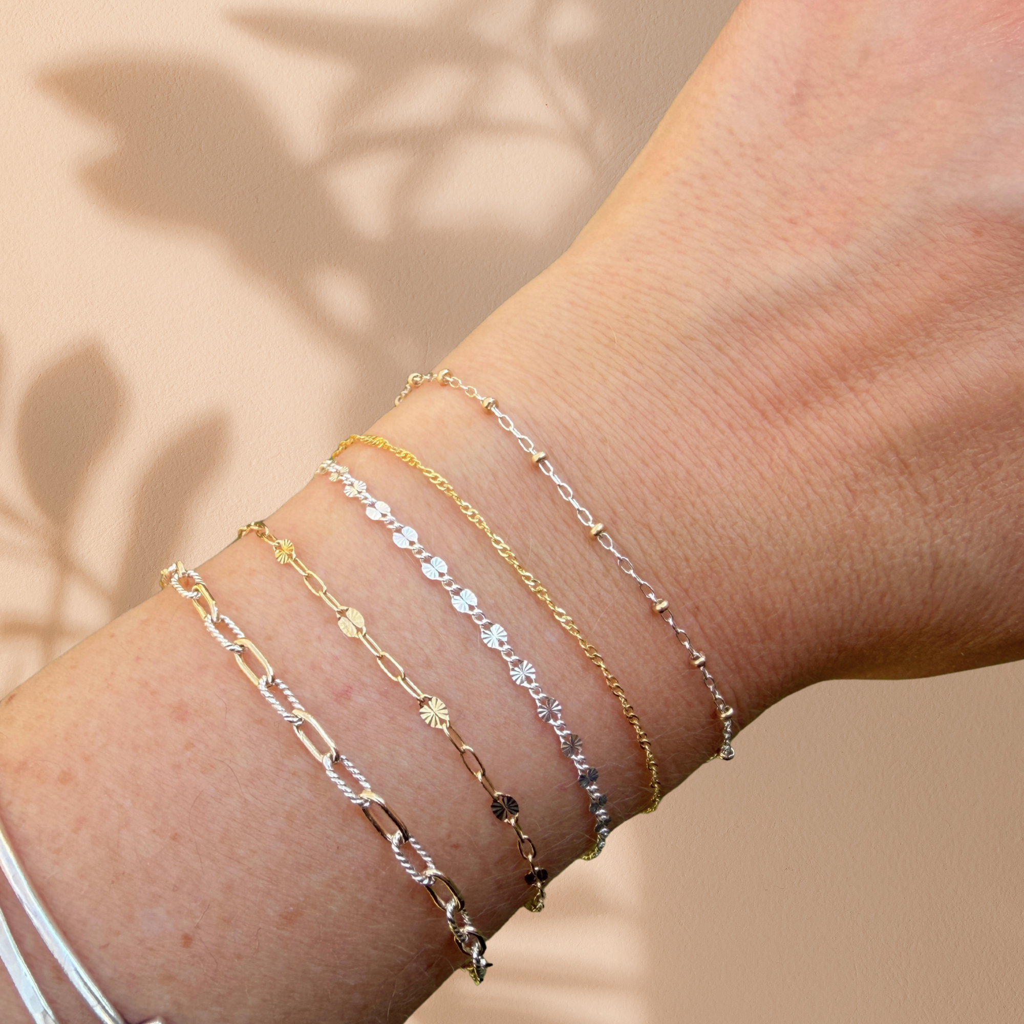 photo of arms with multiple gold and silver permanent bracelets