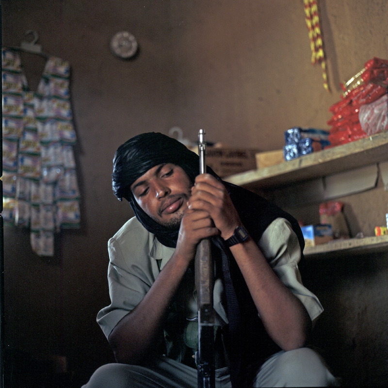 Amouden, a rebel fighter, takes a break in a small provision shop.