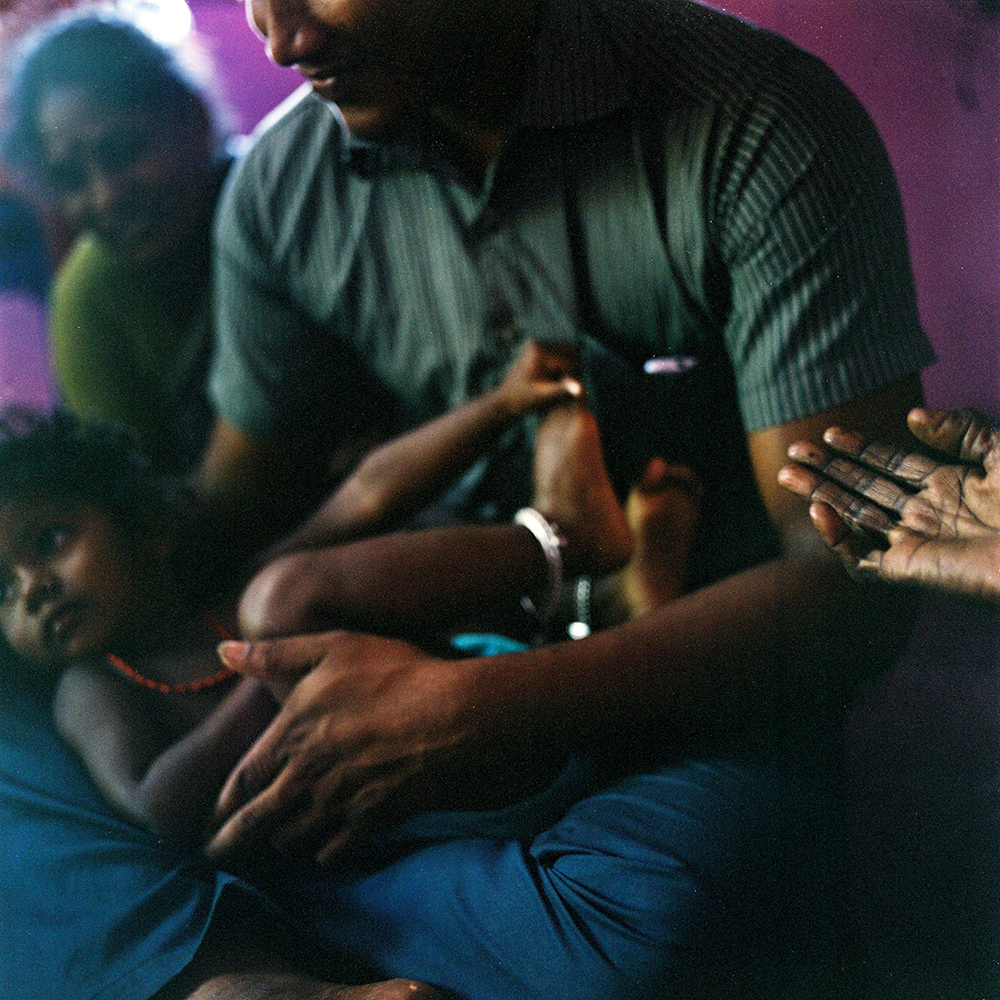   Mohana holds her niece while sitting with her family in their house in the village of Devanapattinam. November 2013&nbsp;  