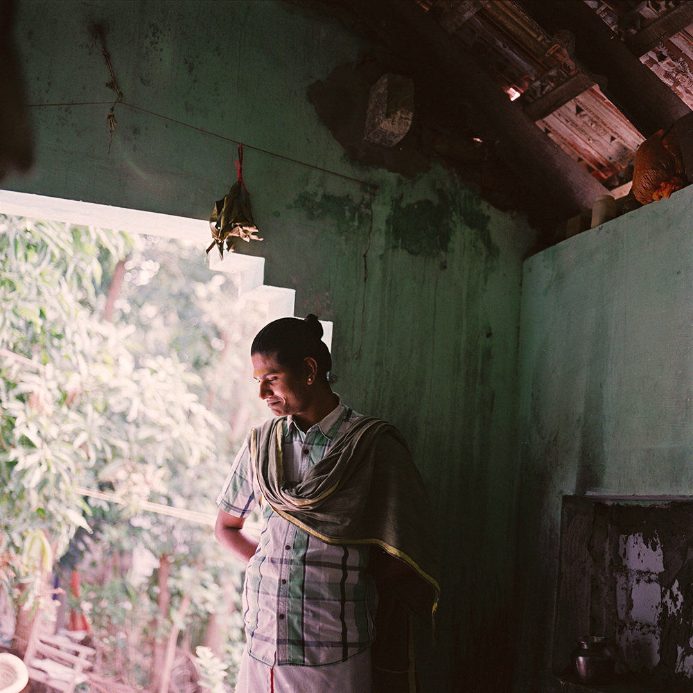   Sivagami standing in the doorway of her house, where she lives with her mother. After an argument with people from her original temple in Devenappatinam, she has built an idol and temple at her house. Her house has become a place where many kothis 