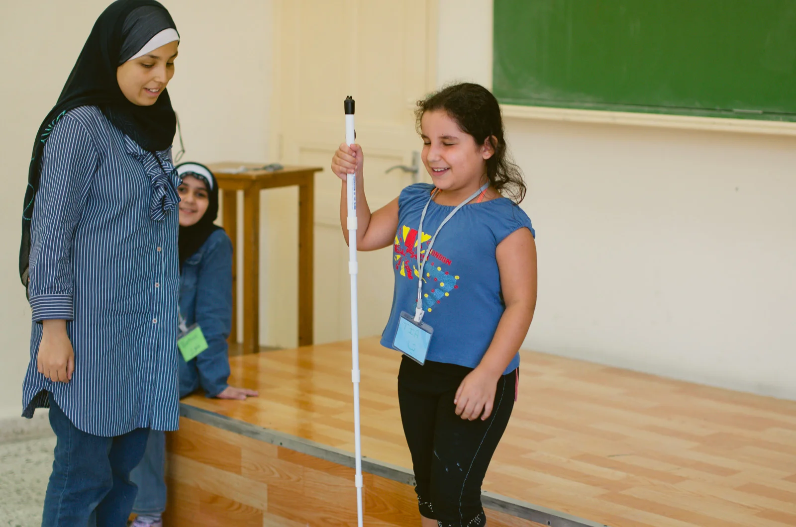 Sara Minkara (left) supervises a girl learning how to use a white cane.